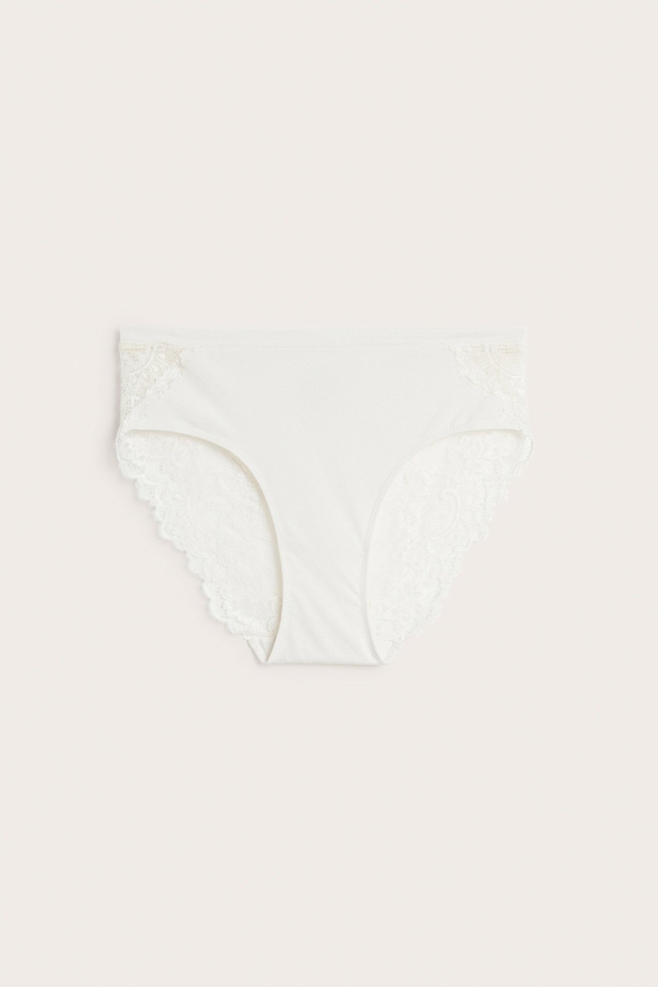 Forfra, offwhite micro-briefs med blondedetaljer på sidene og benåpningene.