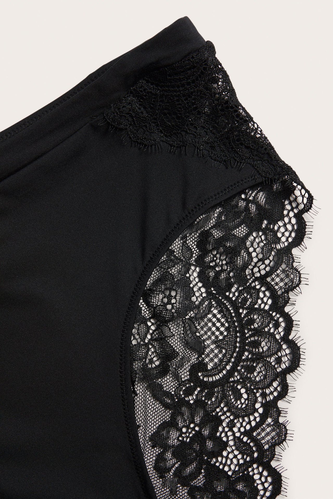 Zbliżenie na czarne majtki z mikrofibry z misternymi koronkowymi wykończeniami.