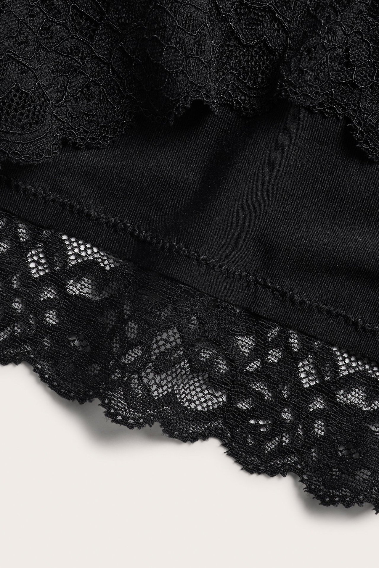 Zbliżenie czarnych fig typu hipster z wysokim stanem, z koronkowymi detalami i mikrofibrą.