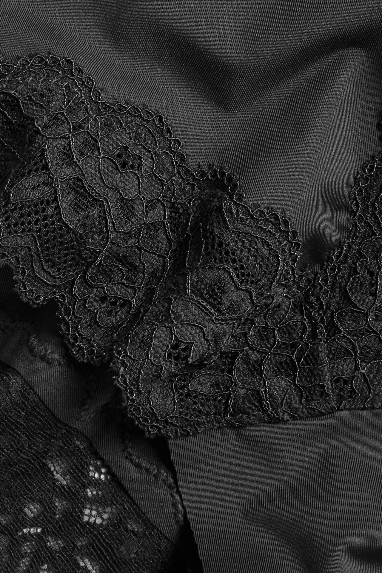 Zbliżenie czarnych fig brazylijskich z delikatną koronkową lamówką w kwiaty przy wycięciu na nogi.