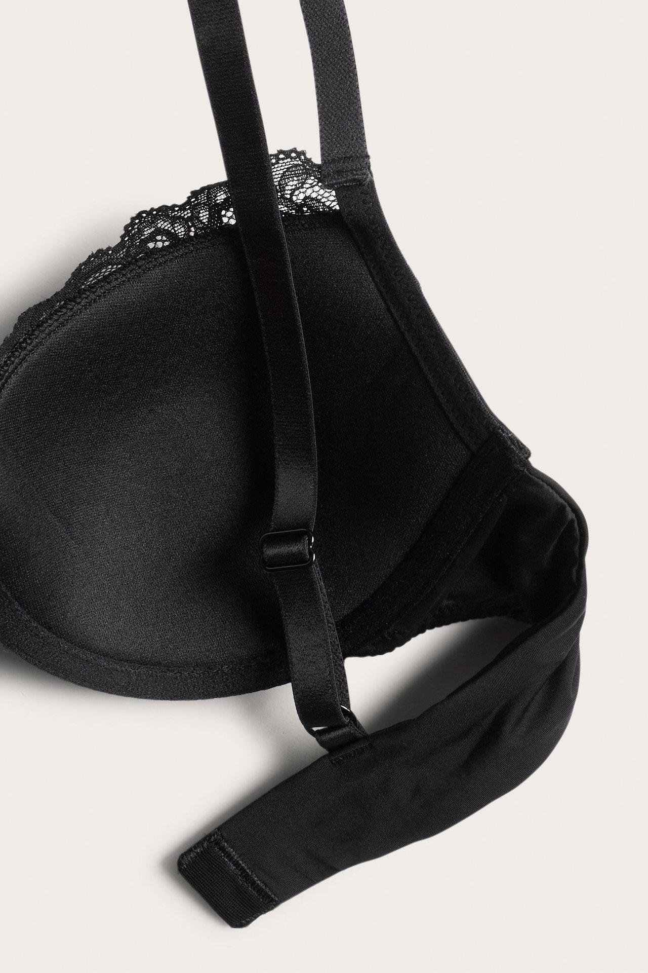 Zbliżenie czarnego, usztywnianego biustonosza z fiszbinami, koronkowym wykończeniem i regulowanymi ramiączkami.