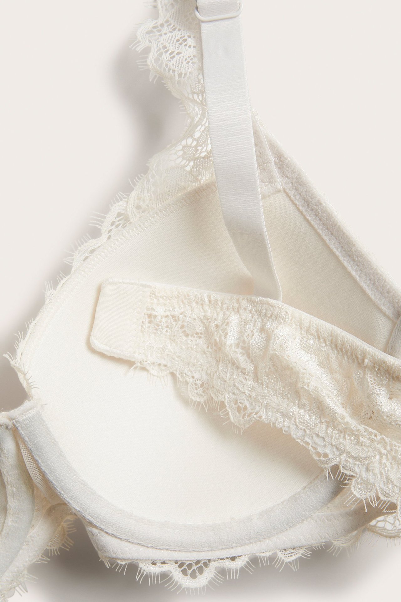 Zbliżenie na biustonosz push-up w kolorze ecru z koronką, delikatnym wykończeniem i regulowanym ramiączkiem.