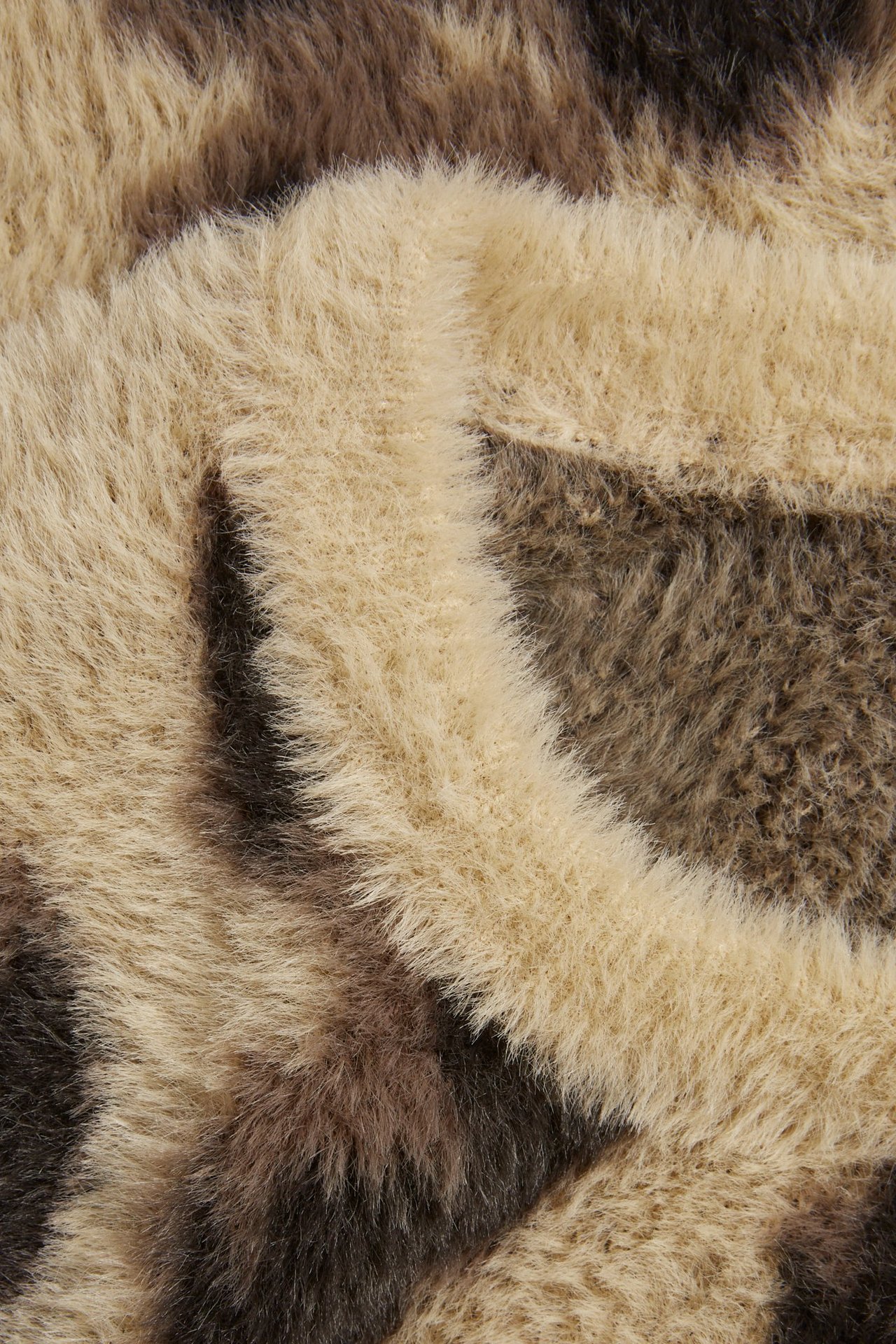 Zbliżenie na beżowy i brązowy, puszysty, żakardowy materiał w panterkę.