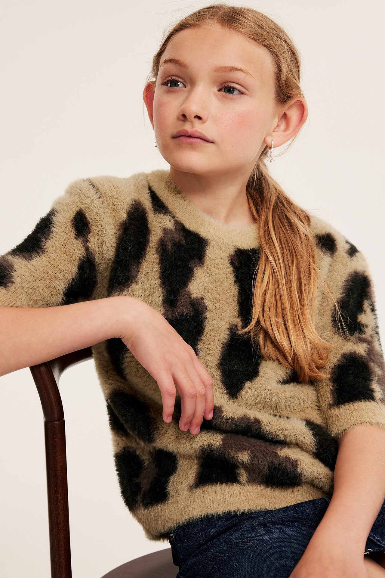 Barnkille i beige jacquardstickad leopardmönstrad tröja, frontvy, med svart och beige mönster.