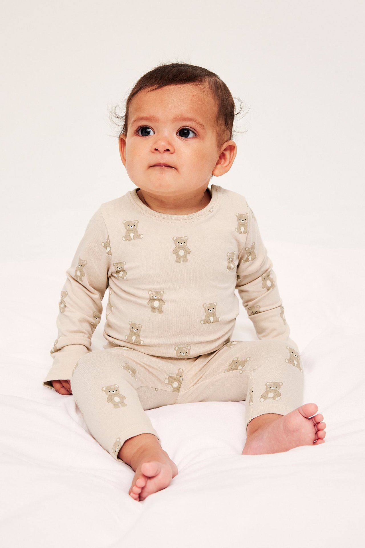 Edestä kuvattu vauva yllään vaaleanbeige pitkähihainen body olkapääneppareilla ja yhteensopivat nallekuvioiset housut.