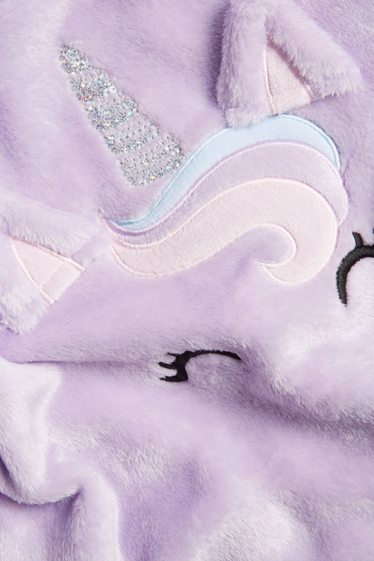 Zbliżenie na jasnofioletowy puszysty sweter dziecięcy z aplikacją jednorożca, cekinowym rogiem i haftem.