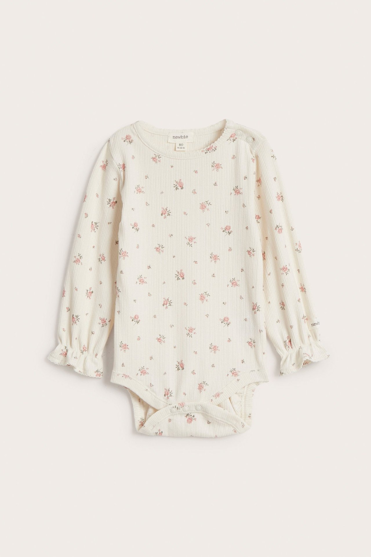 Widok z przodu: Ecru prążkowane body niemowlęce w różowy kwiatowy wzór, z długimi falbankowymi rękawami.