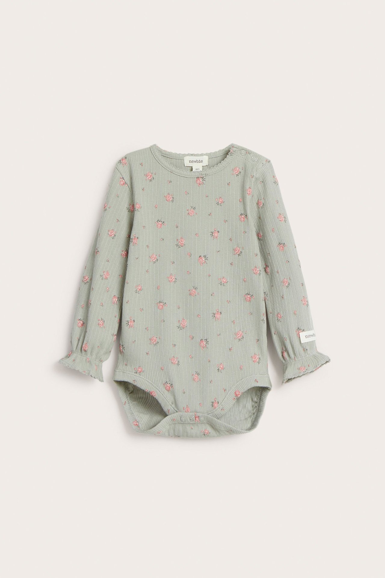 Edestä: vauvan vihreä ribbineulebody kukkakuviolla, pitkät röyhelöhihat ja picot-reunus.