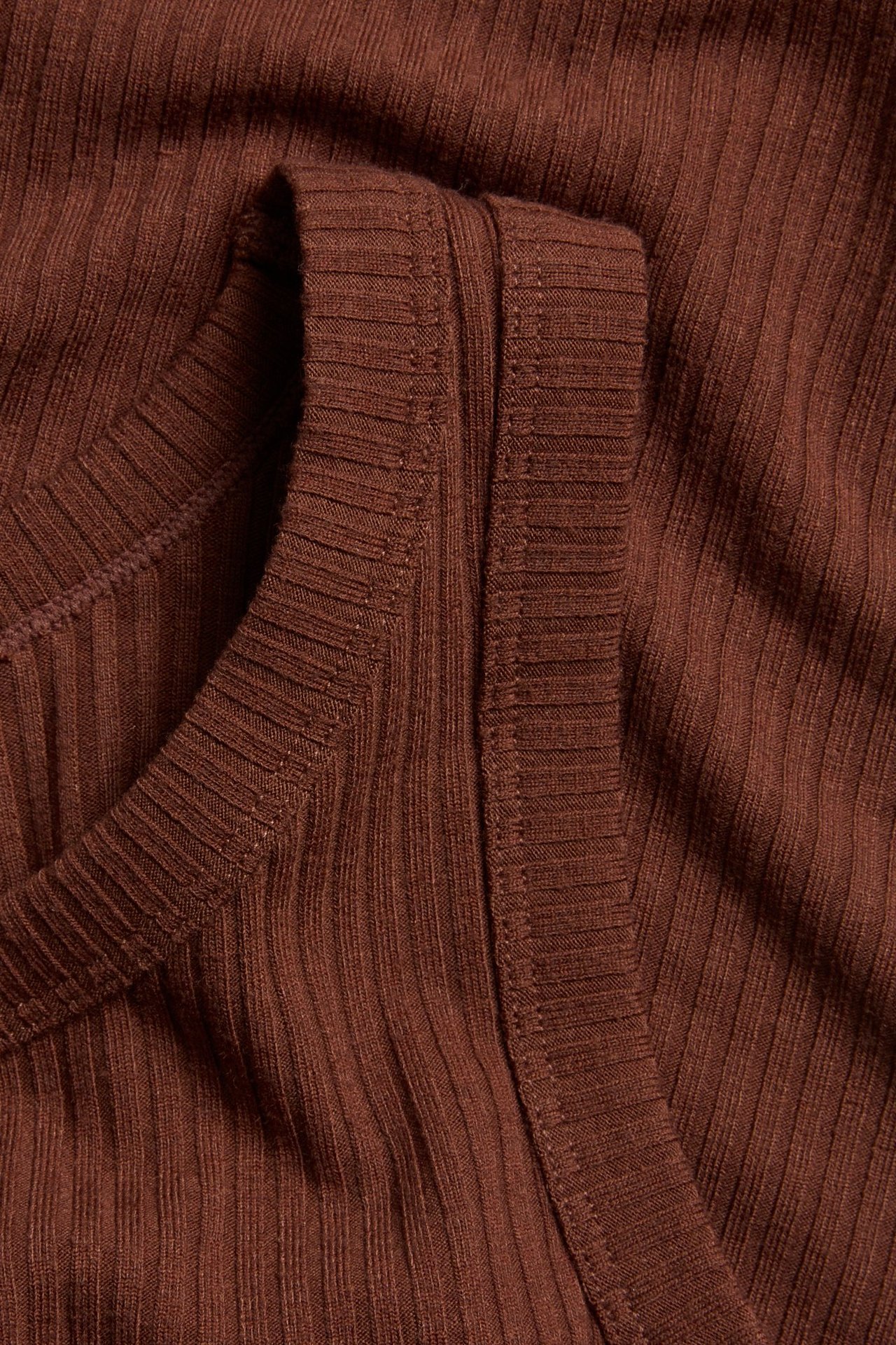 Zbliżenie brązowego prążkowanego topu na ramiączkach z dekoltem w serek.