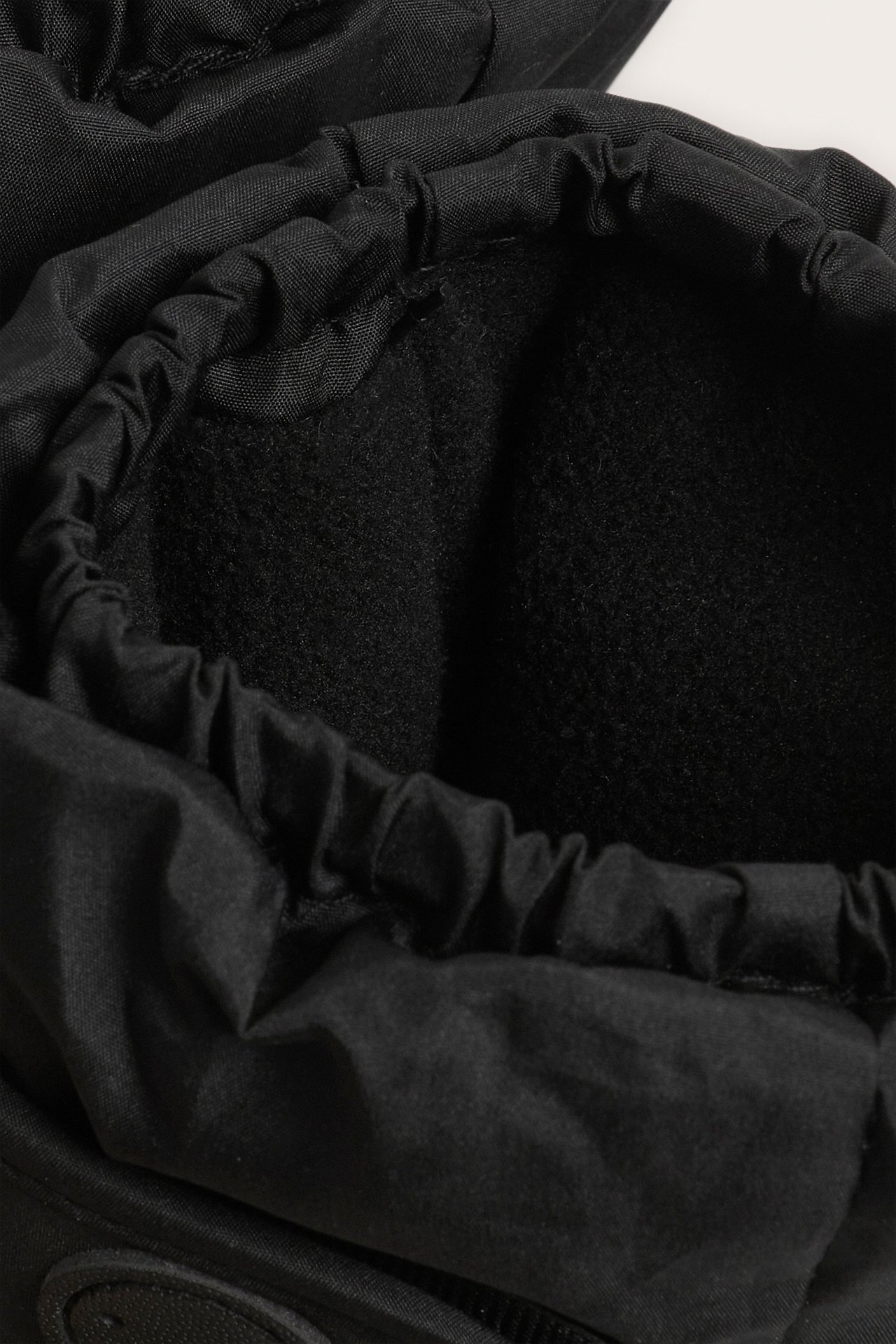 Lähikuva mustista vettähylkivistä vauvan tossuista, joissa fleecevuori ja joustava aukko.