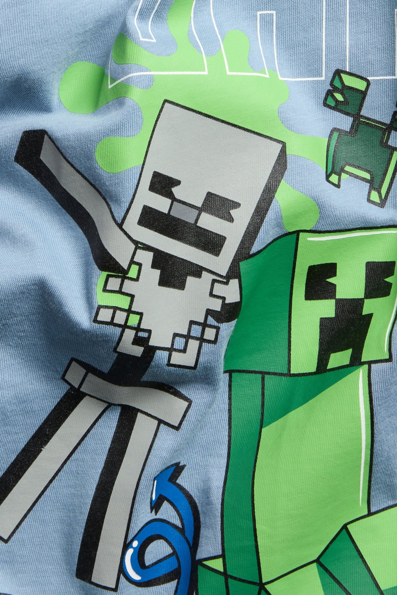 Widok z bliska, z przodu, jasnoniebieskiej bawełnianej koszulki dla dziecka z nadrukiem Minecraft.