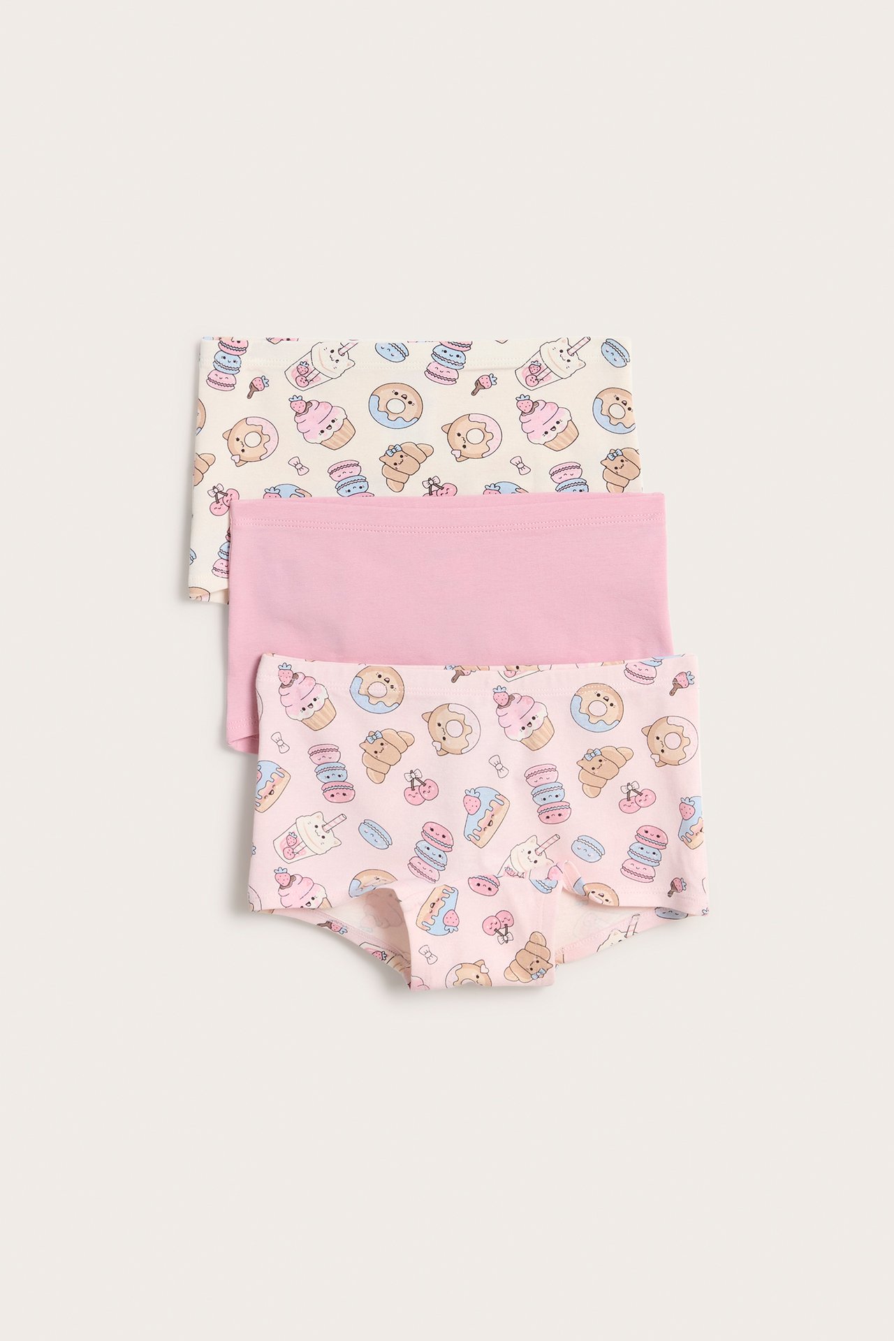 Framifrån: 3-pack boxertrosor för barn; en offwhite mönstrad, en ljusrosa mönstrad, en enfärgad ljusrosa.