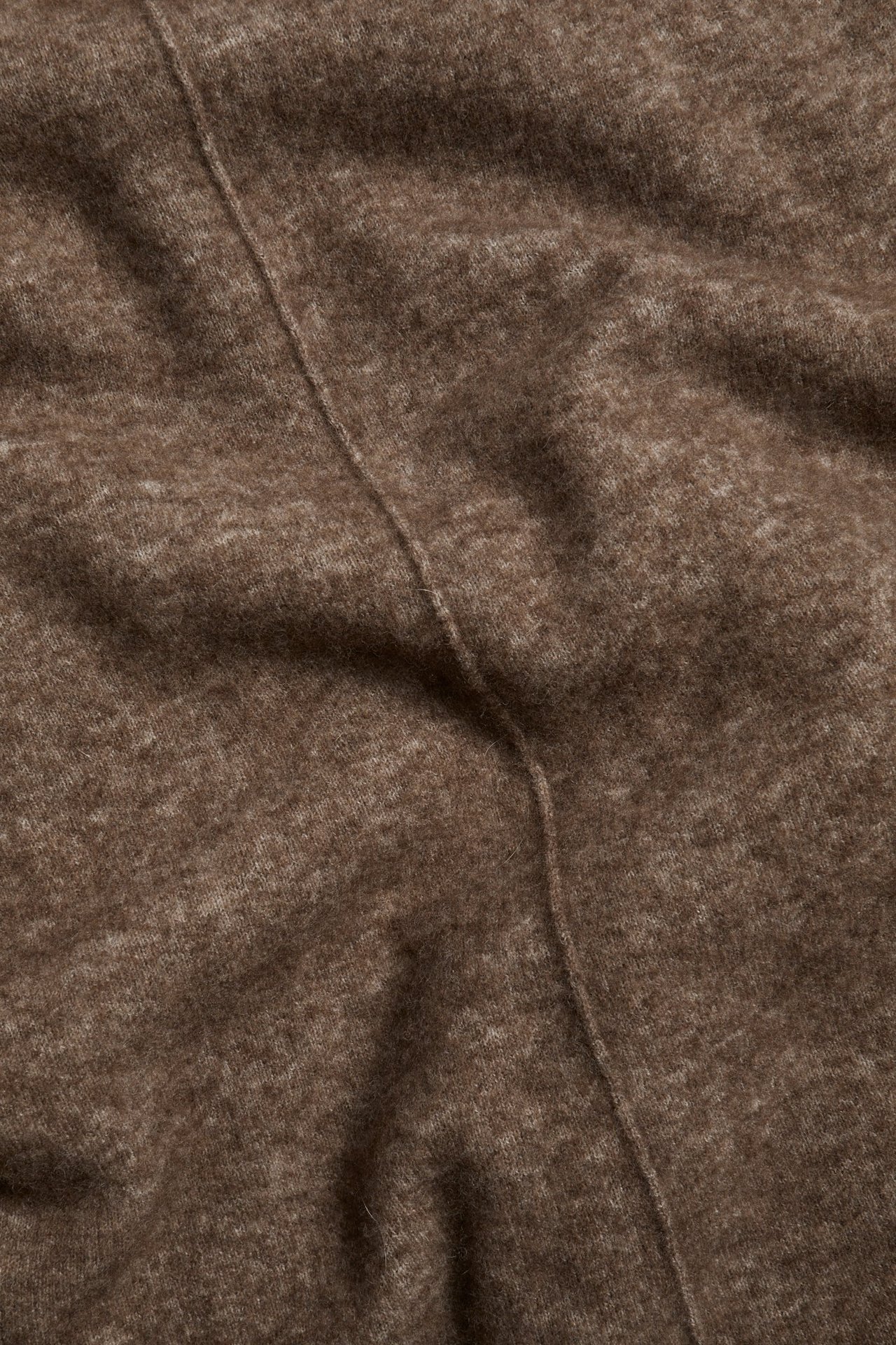 Zbliżenie brązowej melanżowej, drobno dzianej spódnicy z mieszanki wełny z ozdobnym szwem.