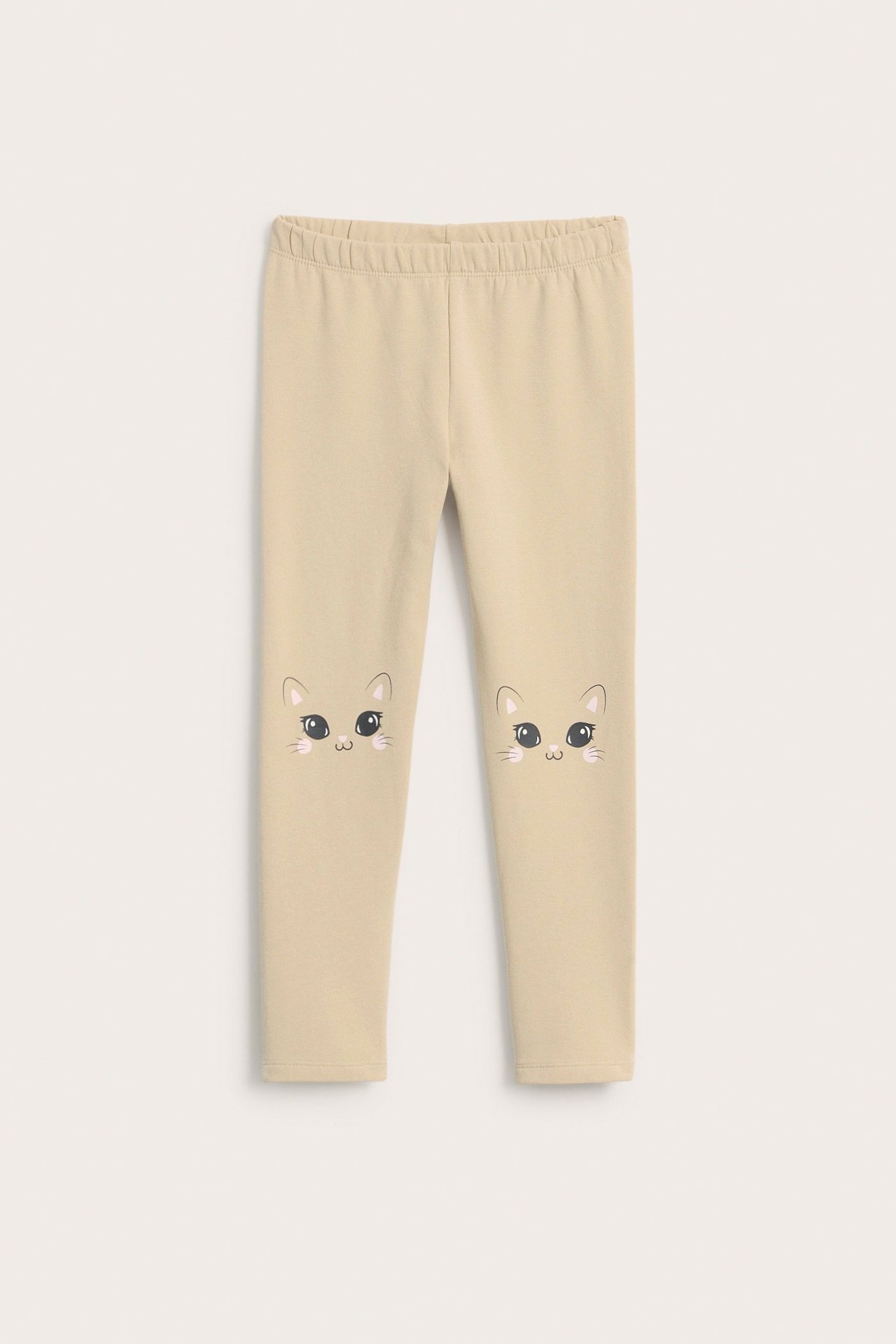 Widok z przodu beżowych legginsów dziecięcych z aplikacjami kocich twarzy na kolanach.