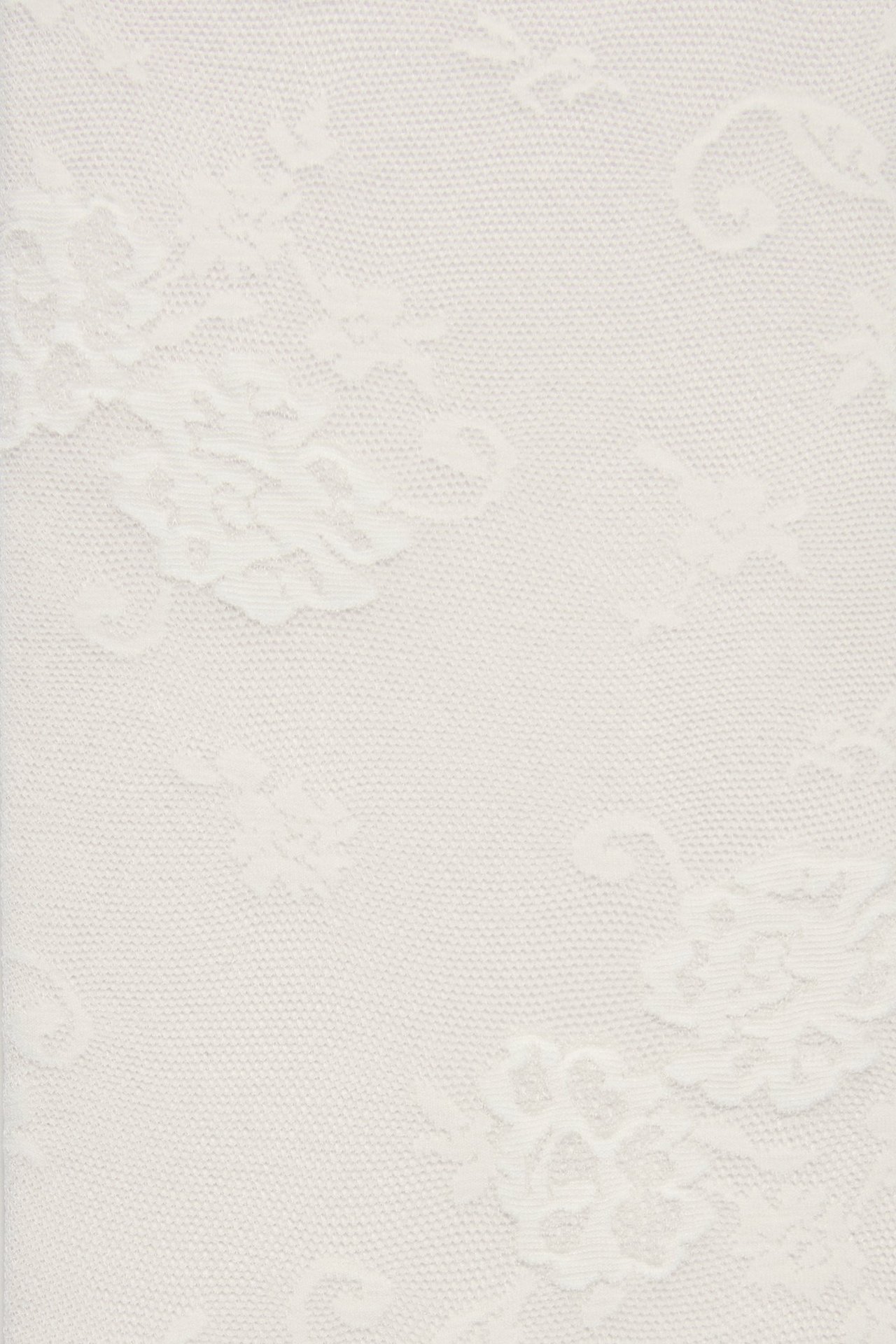 Zbliżenie na rajstopy w kolorze ecru z koronkowym wzorem.