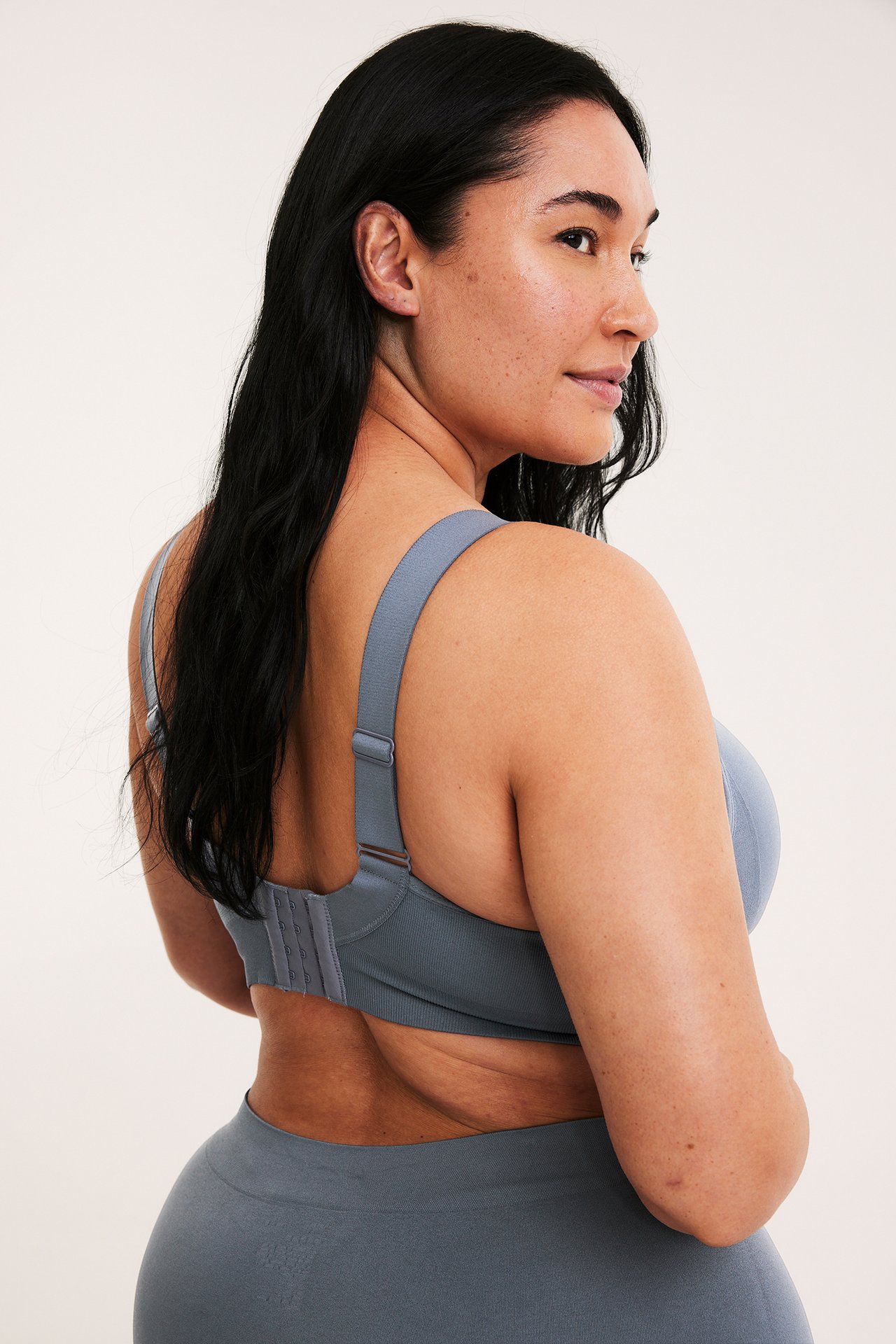 Bakside av kvinne i en mørkeblå sømløs bøylefri BH med matchende sømløse underdeler.