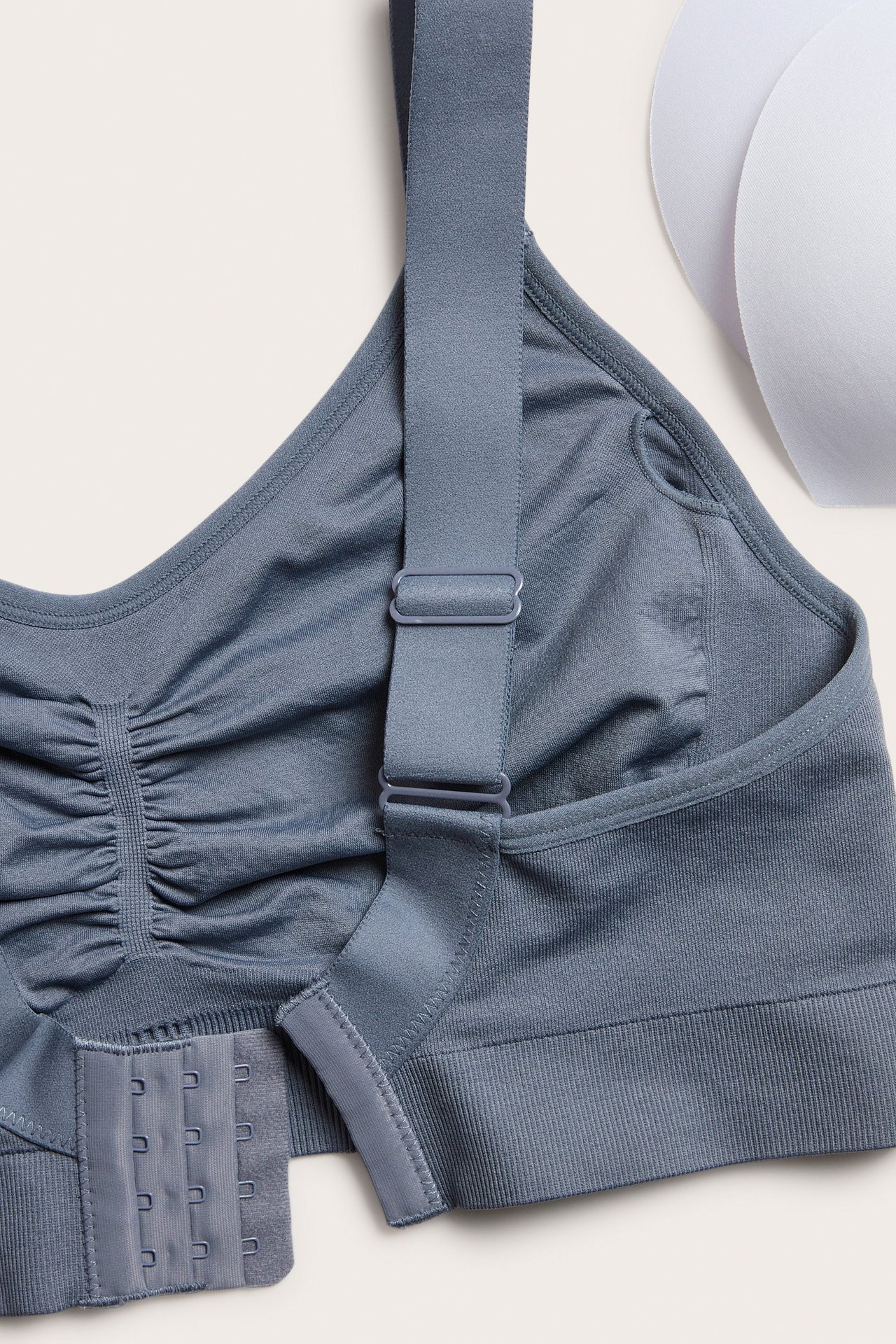 Zbliżenie na granatowy bezszwowy biustonosz bez fiszbin, z regulowanymi ramiączkami, zapięciem na haftki i wyjmowanymi wkładkami.