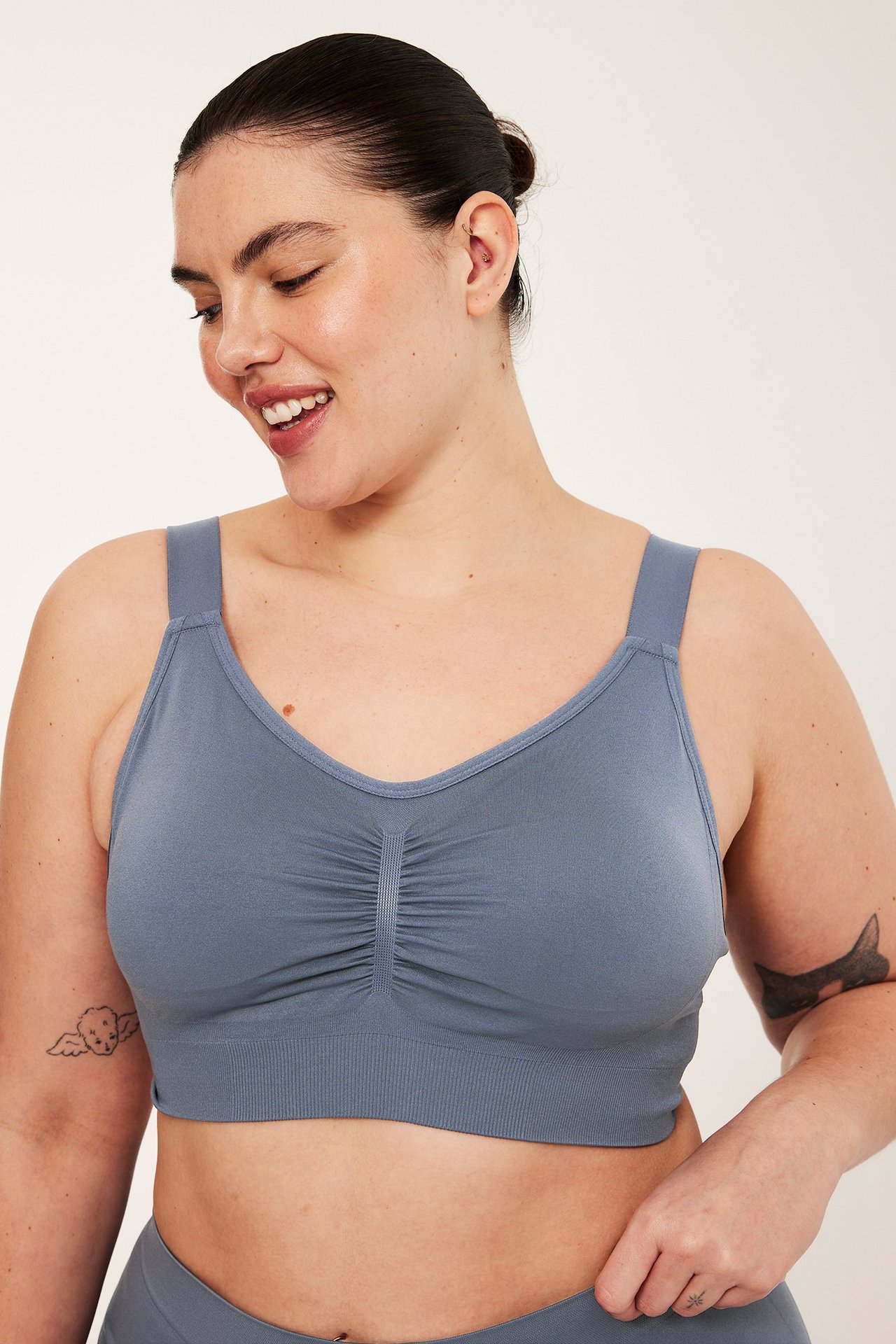 Widok z przodu kobiety w granatowym bezszwowym biustonoszu bez fiszbin z marszczonym przodem.