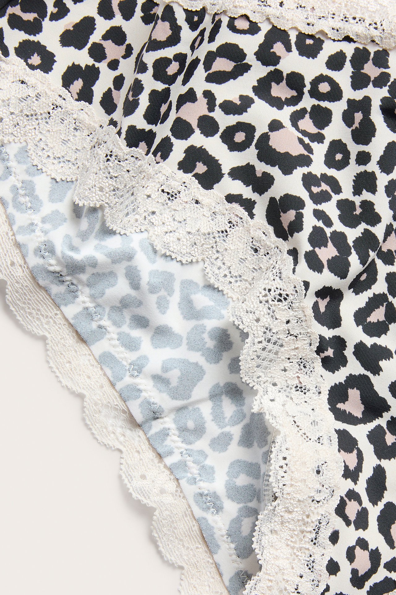 Nærbilde av dame beige leopardmønstret cheeky-truse med kremfarget blondekant.