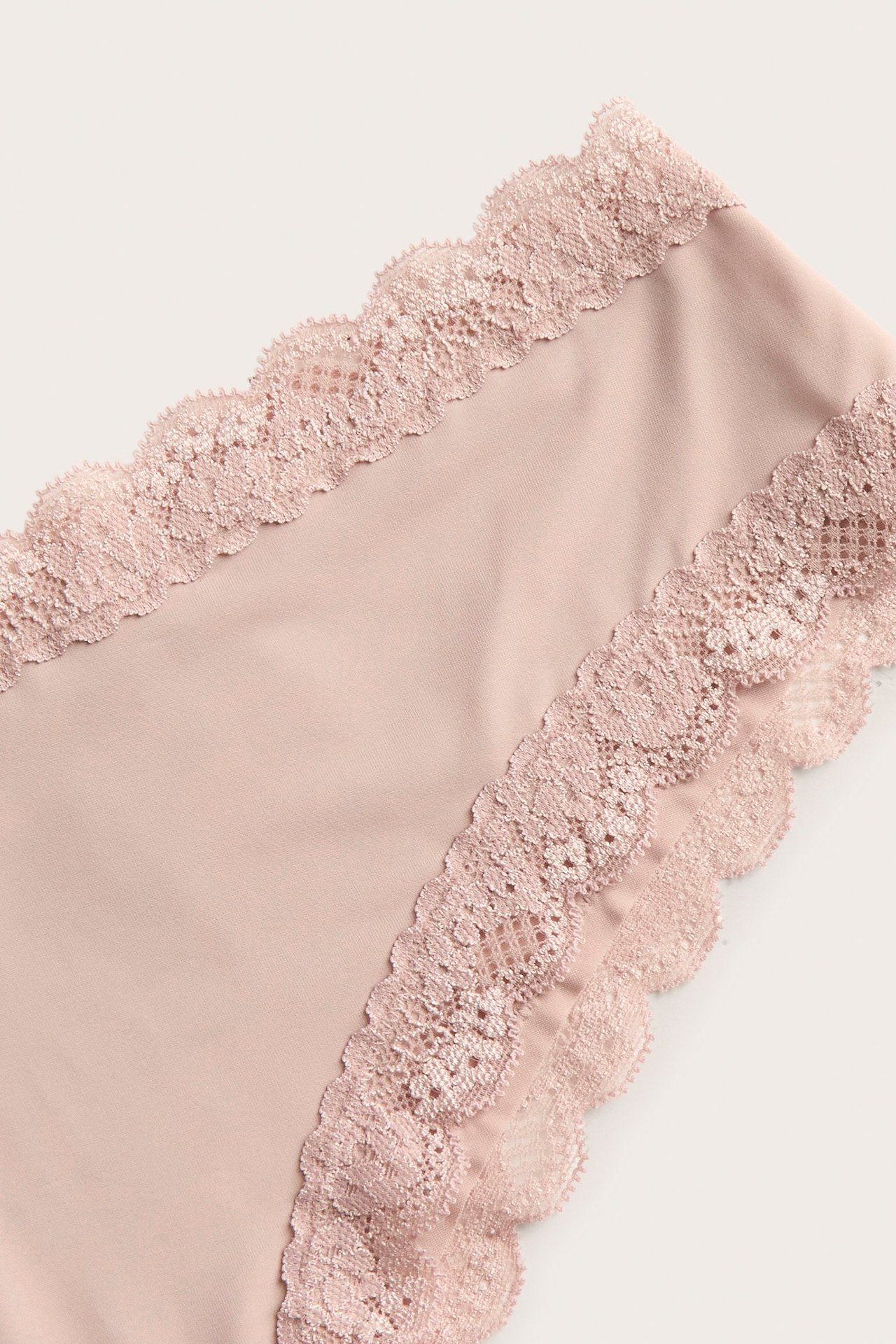 Nærbilde av lys rosa cheeky truser i mikrokvalitet med delikat blondekant.