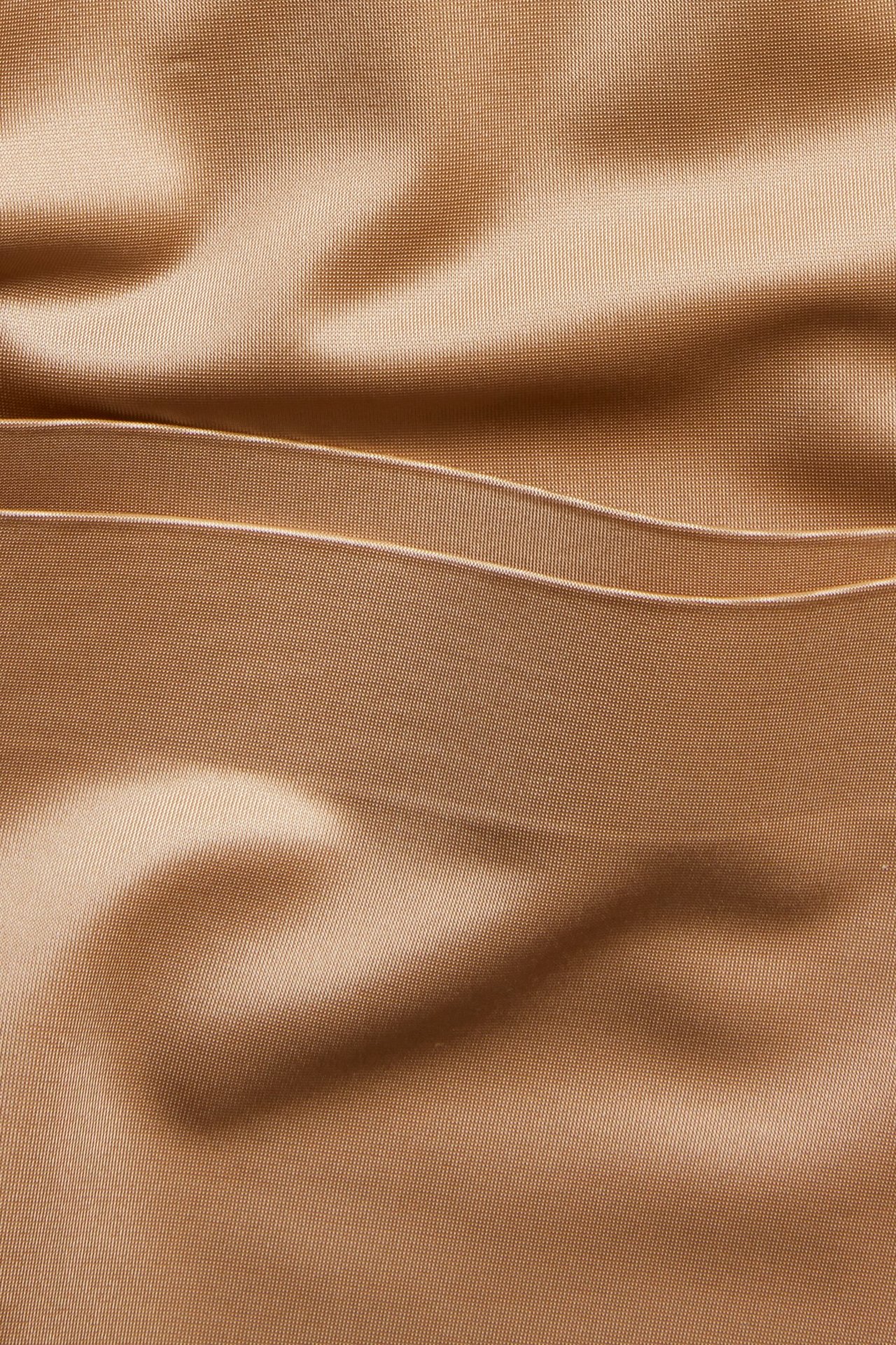 Zbliżenie na brązowe szorty modelujące z mikrosatyny z bezszwowymi krawędziami i delikatnymi fałdami.