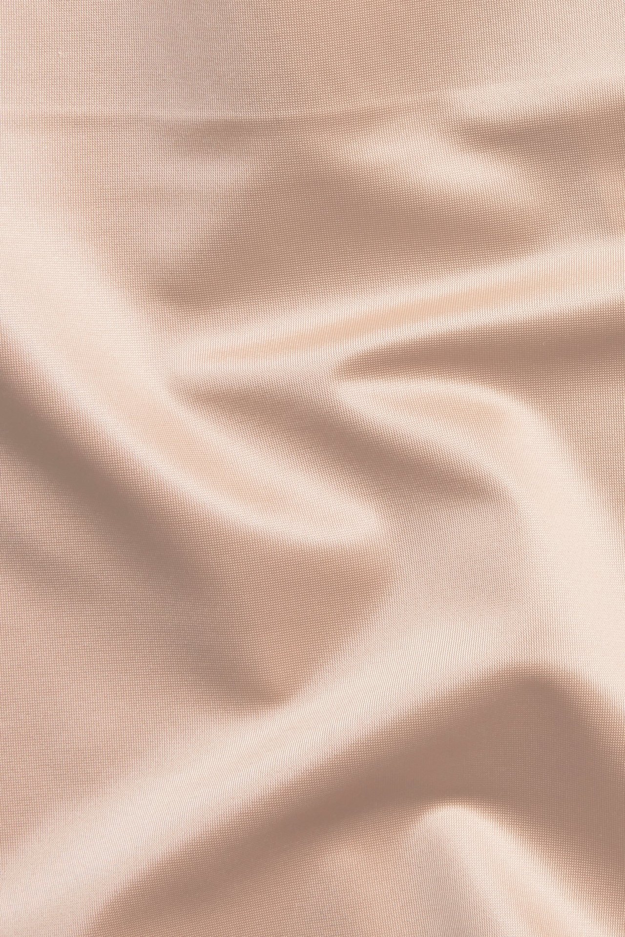 Zbliżenie na jasnoróżowy, gładki materiał satynowy mikro o delikatnie błyszczącej fakturze.