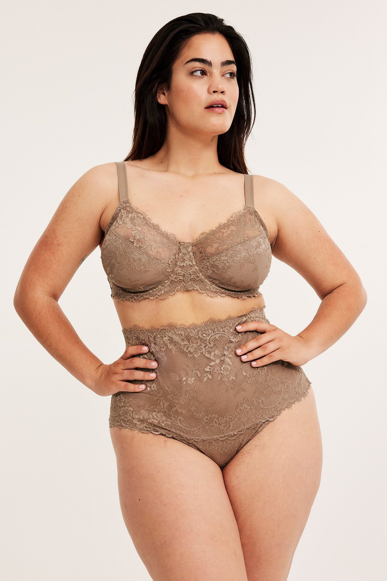 Frontbilde av en kvinne i beige høytlivs blondestringtruse med matchende blonde-BH.