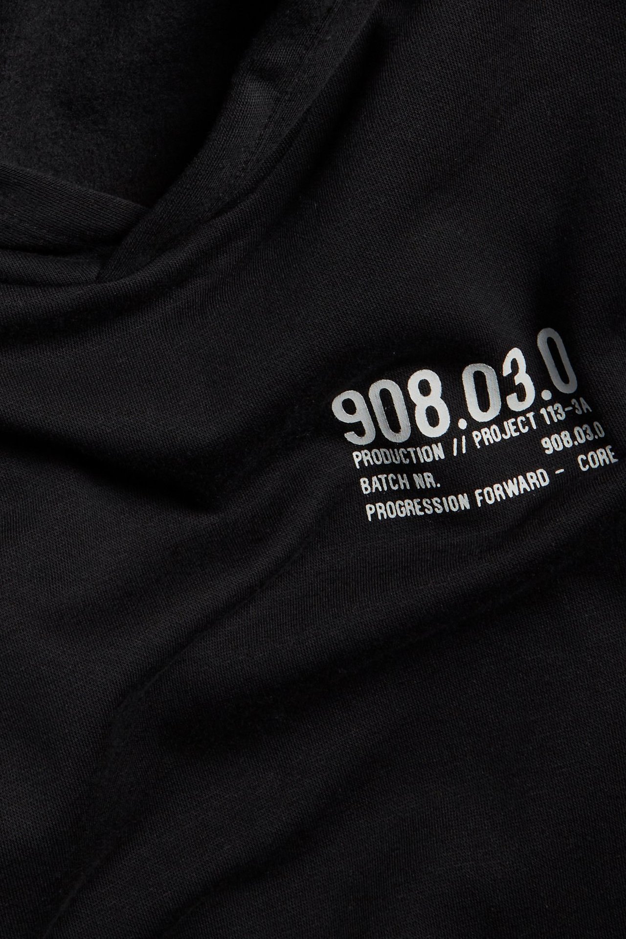 Zbliżenie czarnej bluzy z kapturem z białym nadrukiem graficznym na piersi.