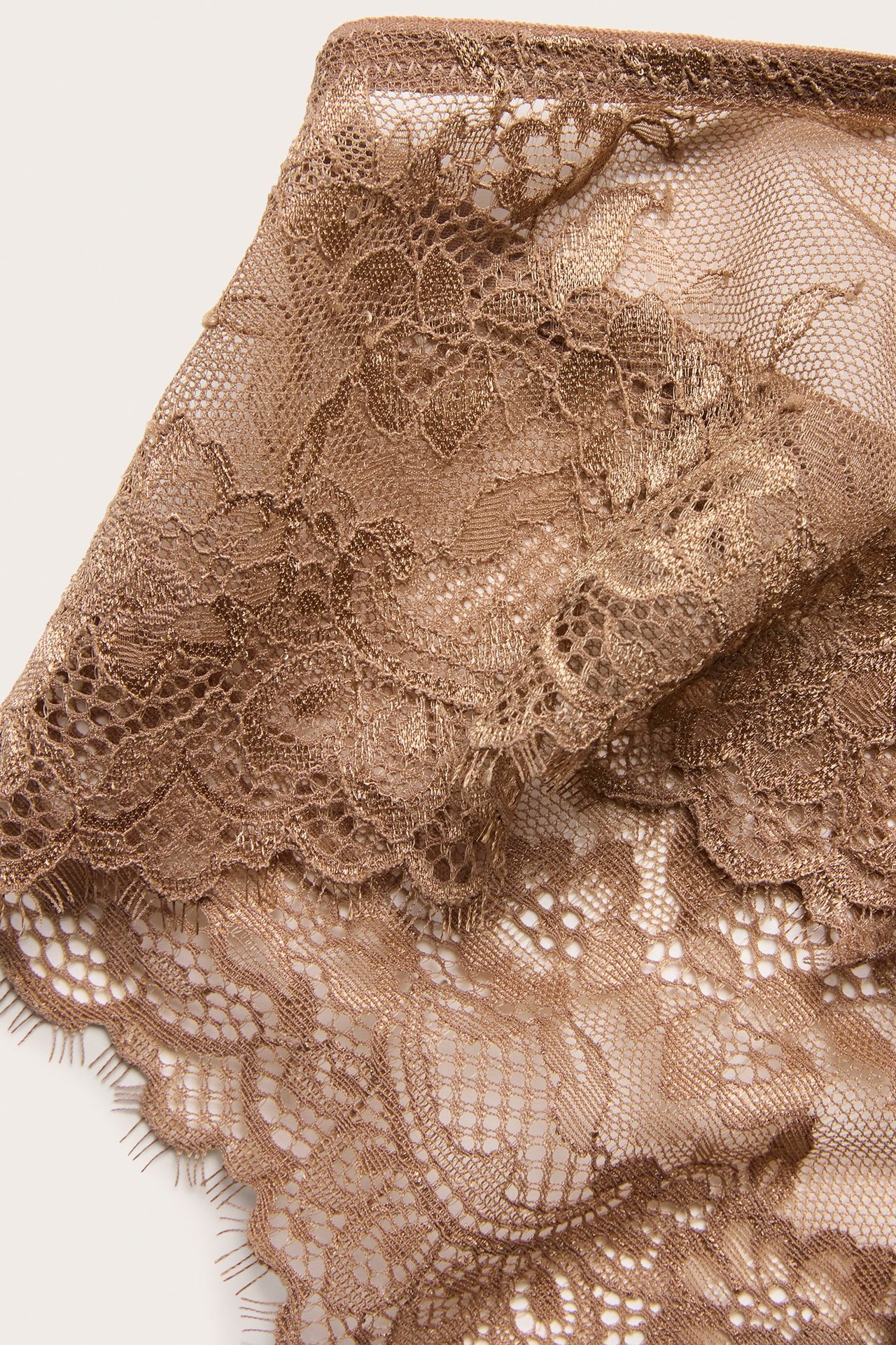 Zbliżenie beżowej koronki eyelash z fig cheeky, ukazujące misterny wzór kwiatowy.