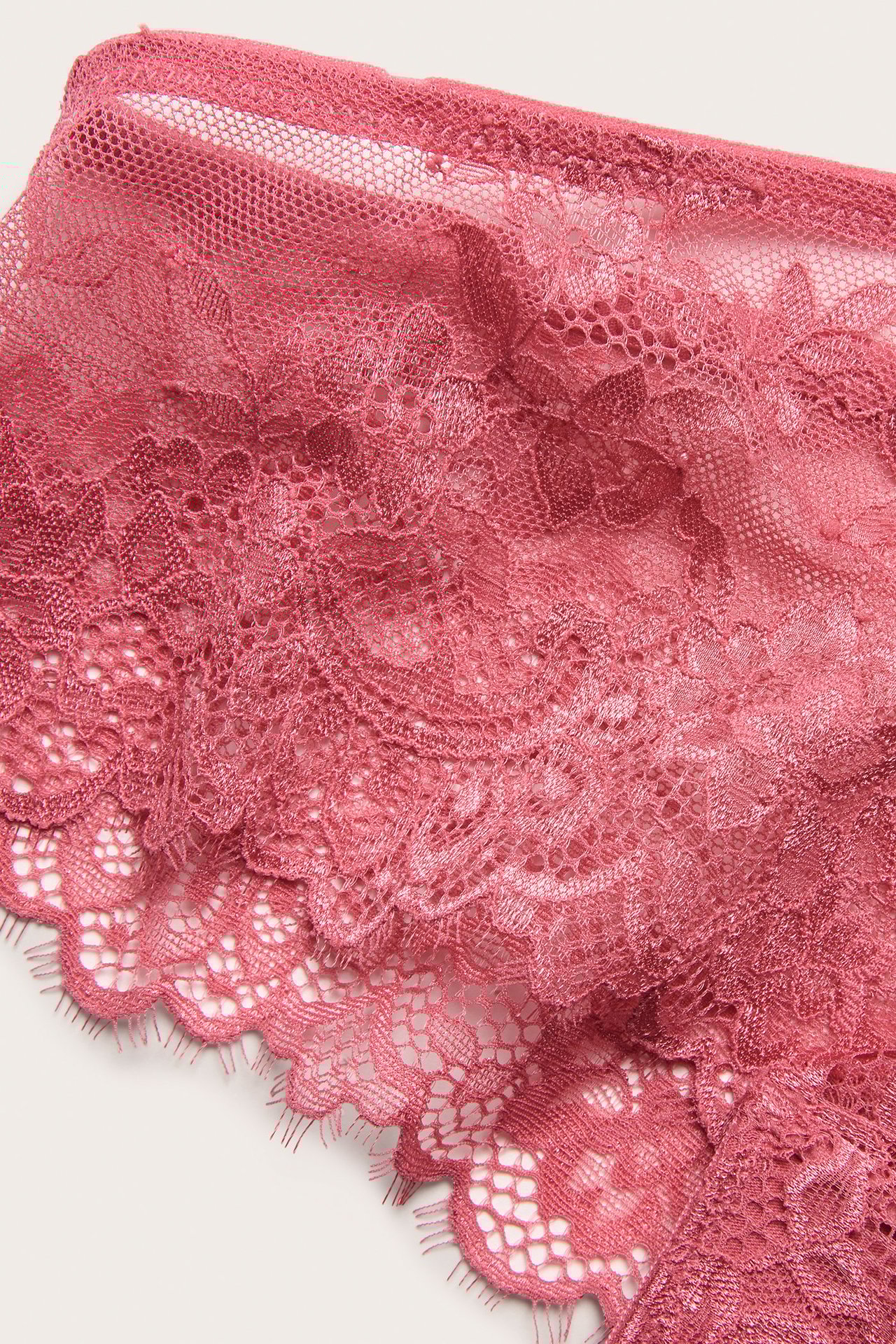 Zbliżenie koralowych damskich fig cheeky z ozdobnej koronki eyelash z kwiatowym wzorem.