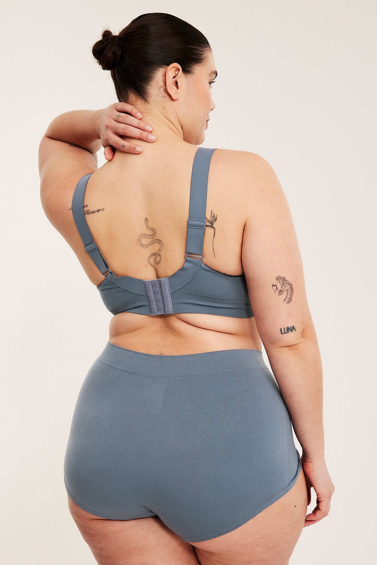 Widok z tyłu kobiety noszącej ciemnoniebieskie bezszwowe bokserki i dopasowany biustonosz.