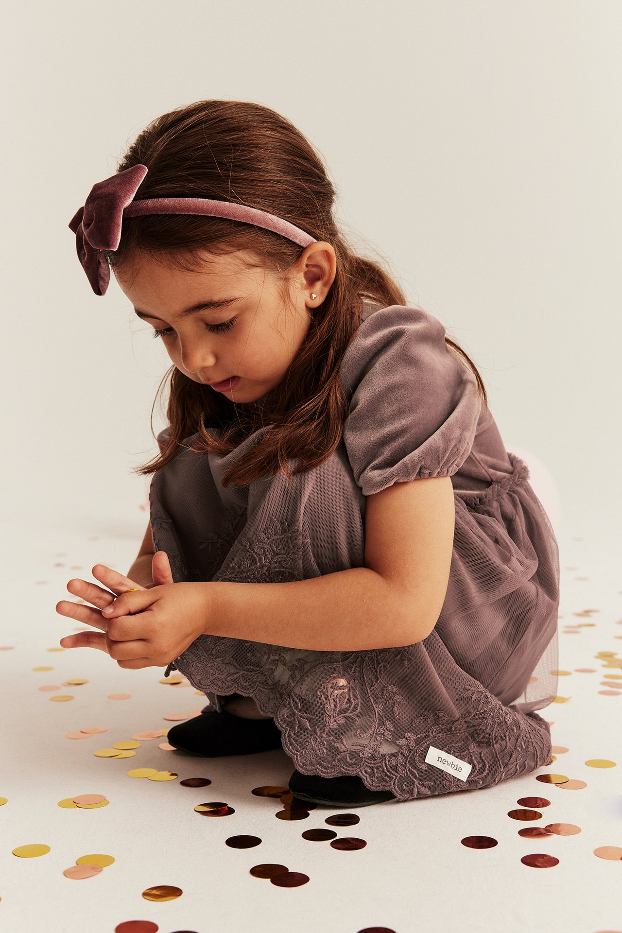 Framsida: Kid i mörkrosa velourklänning med puffärmar, broderad meshkjol och sammetsrosetthårband.