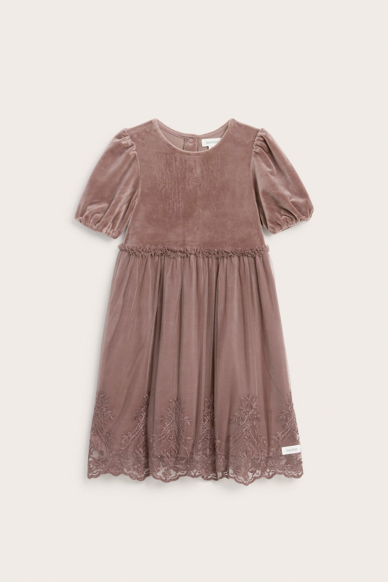 Frontvy av en mörkt rosa velourklänning för barn med puffärmar och broderad meshkjol.