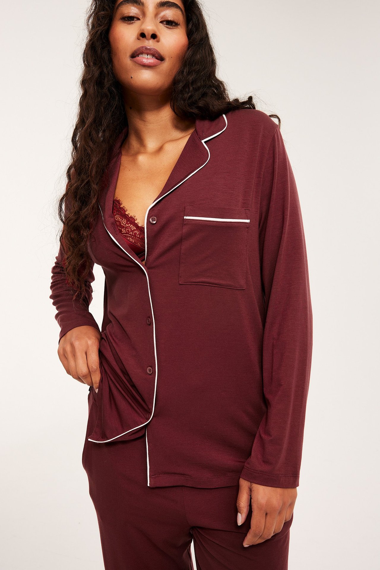 Nainen punaisissa pitkähihaisissa pyjamaa, valkoinen reunus, rento istuvuus, etunäkymä.