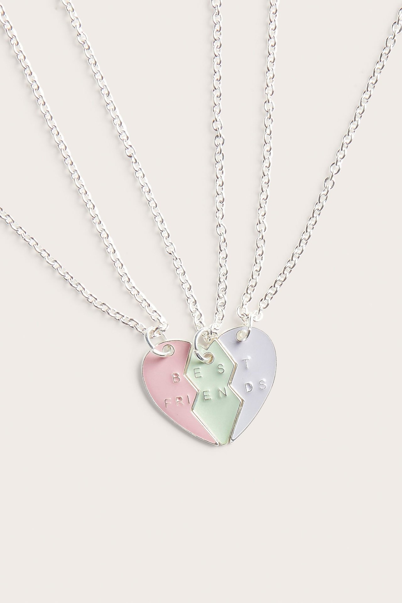 Närbild på tre bästa vänner-halsband, silverkedjor, pastellfärgade hjärtberlocker.