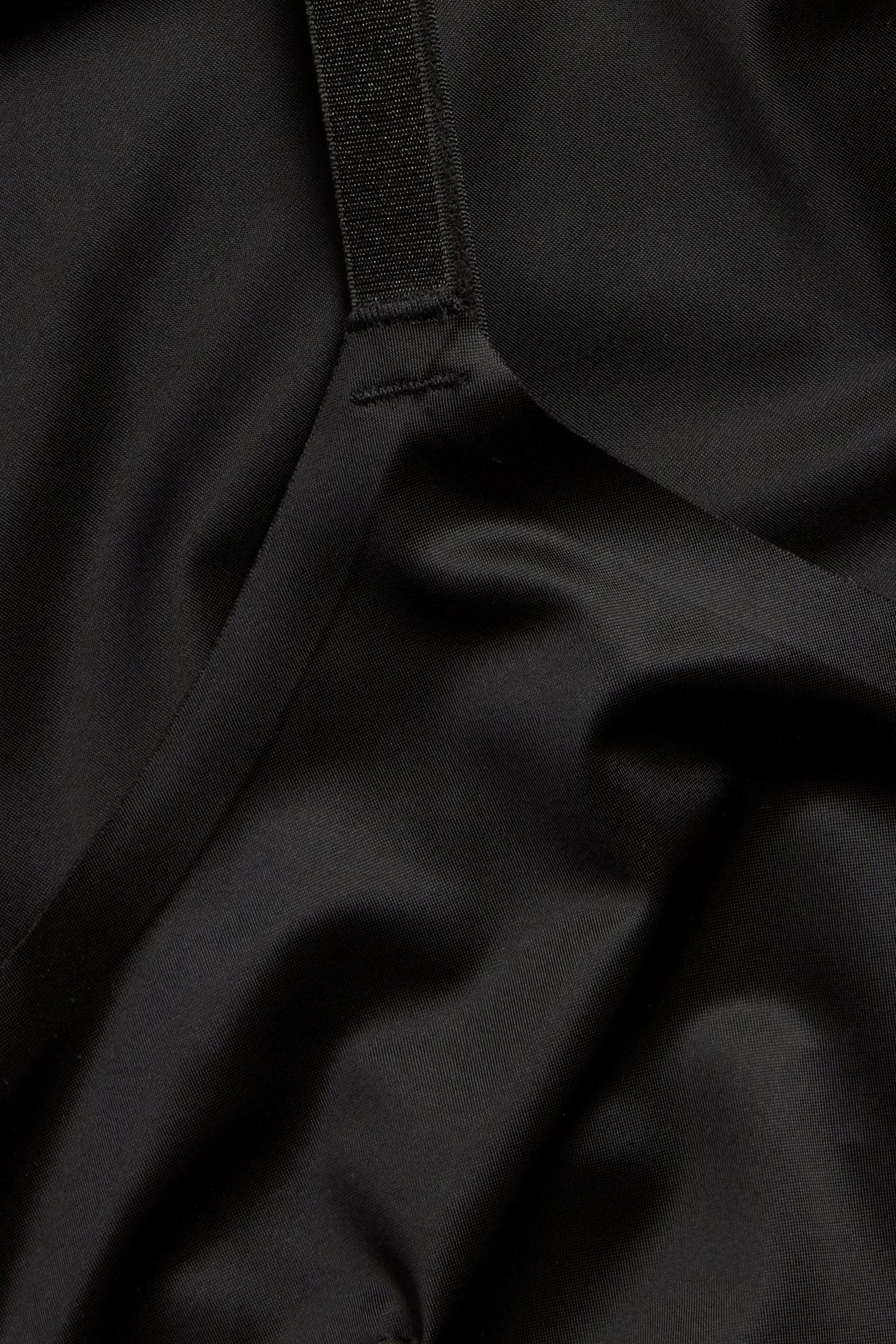 Zbliżenie czarnej modelującej halki z satynowym wykończeniem i regulowanym ramiączkiem.