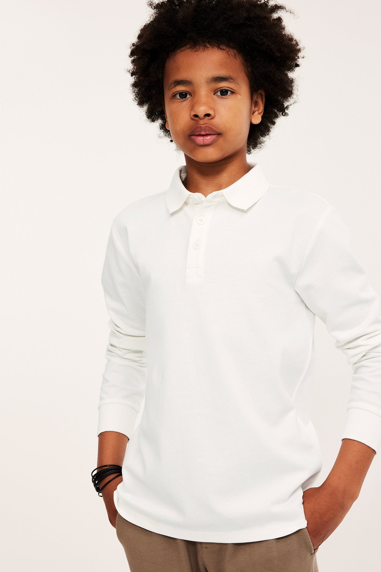 Lasten valkoinen pitkähihaisinen polo-paita kauluksella ja kolmella napilla.