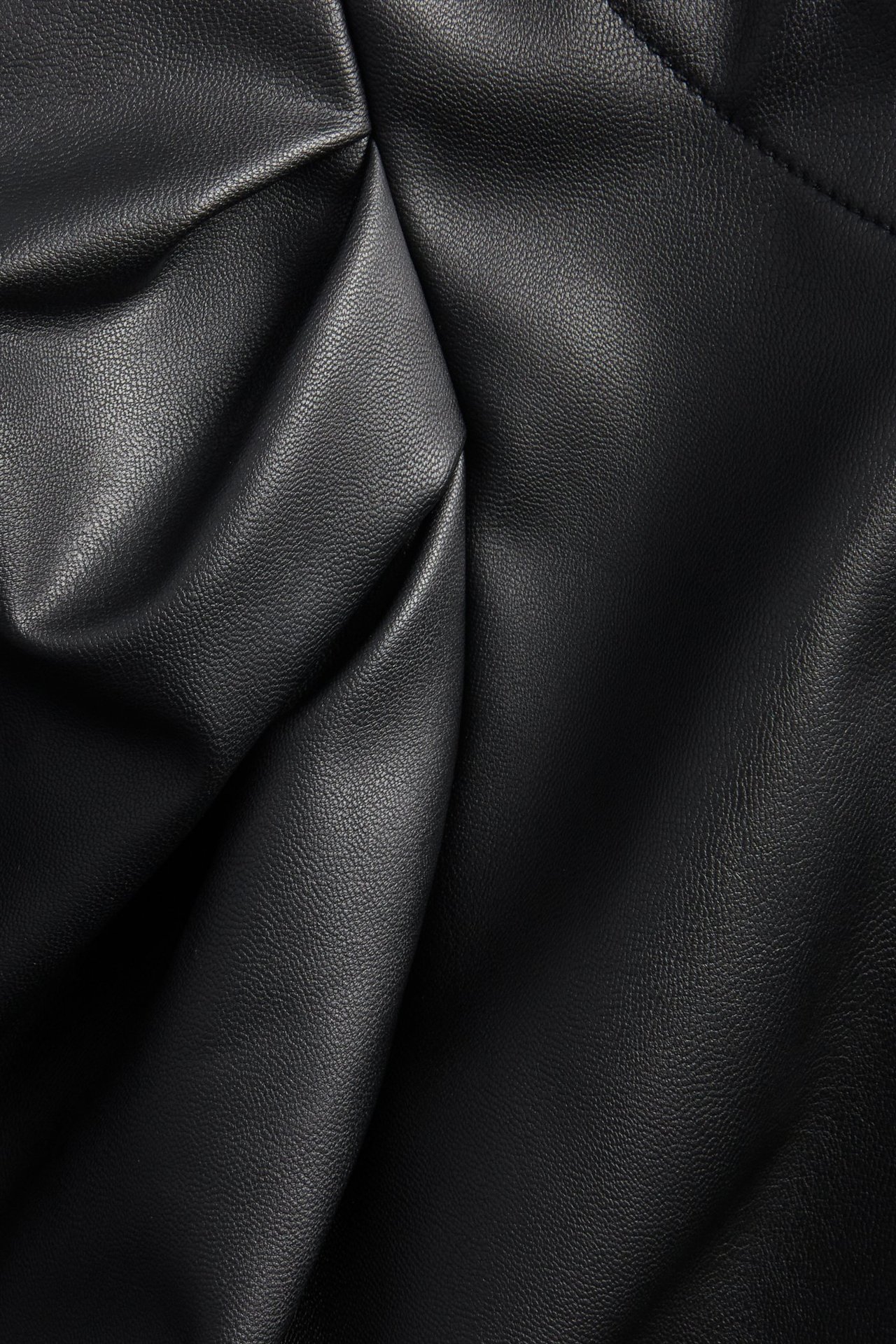 Zbliżenie czarnego, teksturowanego materiału PU z miękkimi fałdami, tkanina na bluzkę.
