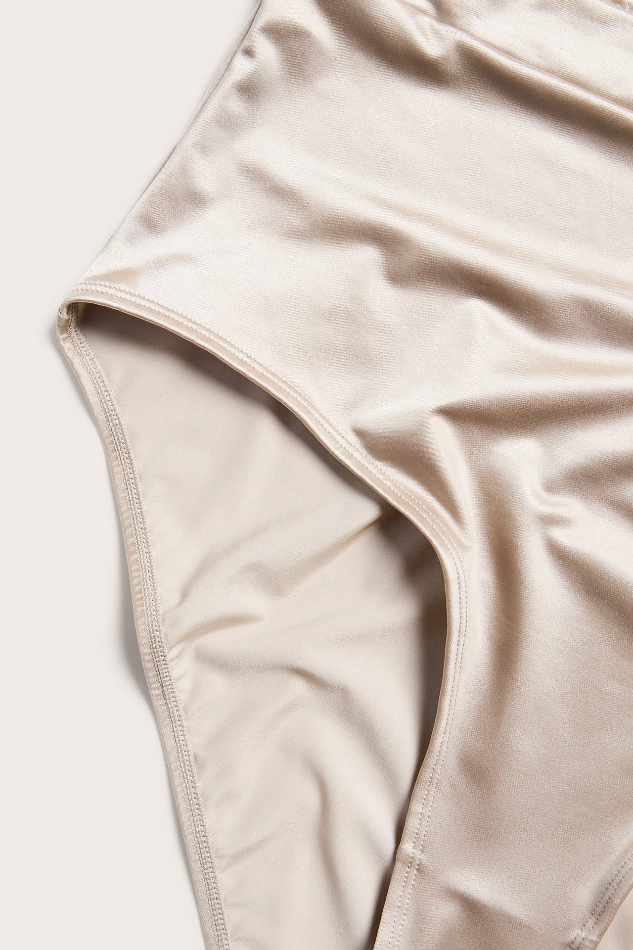 Lähikuva vaaleanpunaisista korkeavyötäröisistä alushousuista, joissa on kiiltävä, yksivärinen kangas.