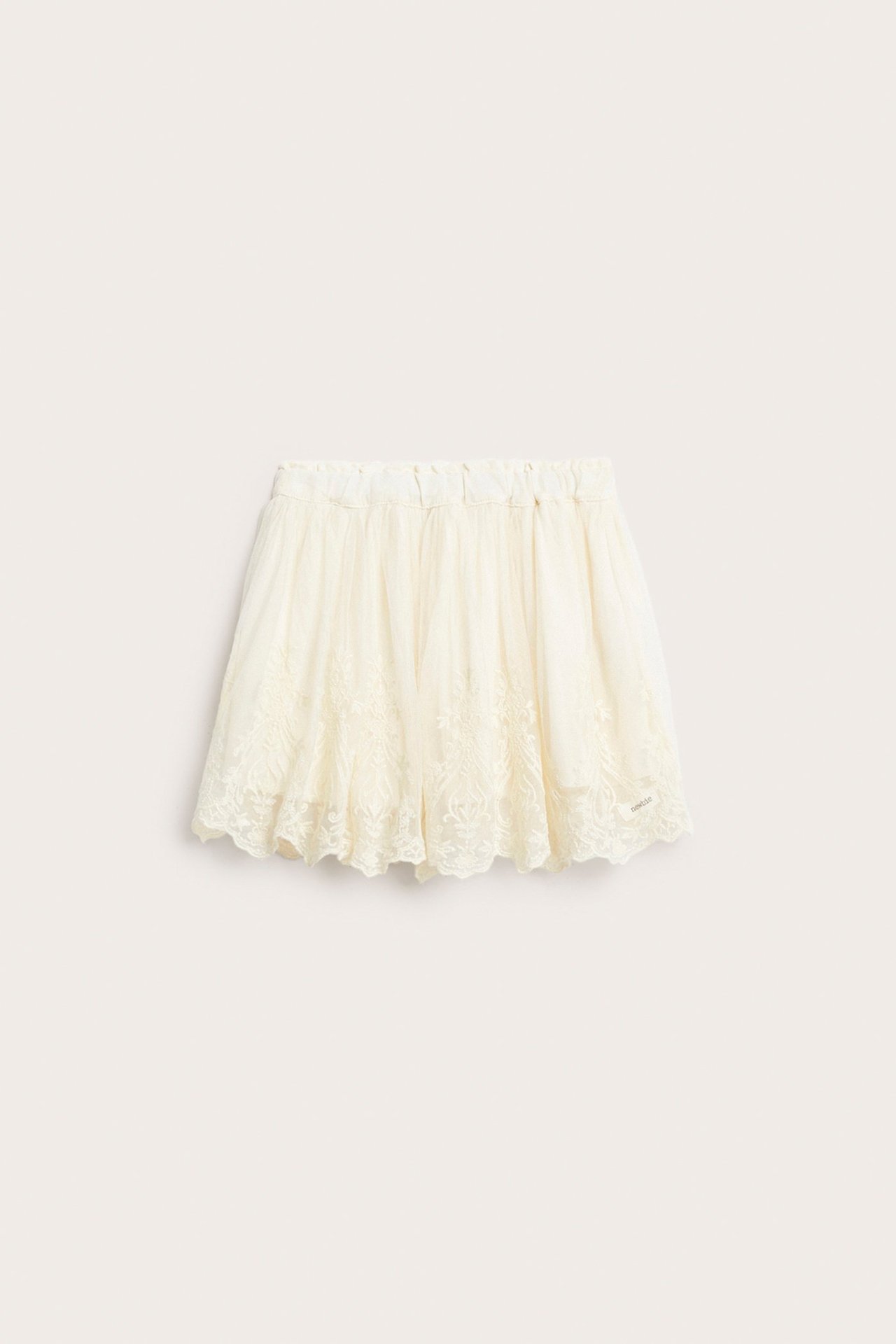 Framifrån: Ljusbeige broderad meshkjol med resår i midjan och foder.