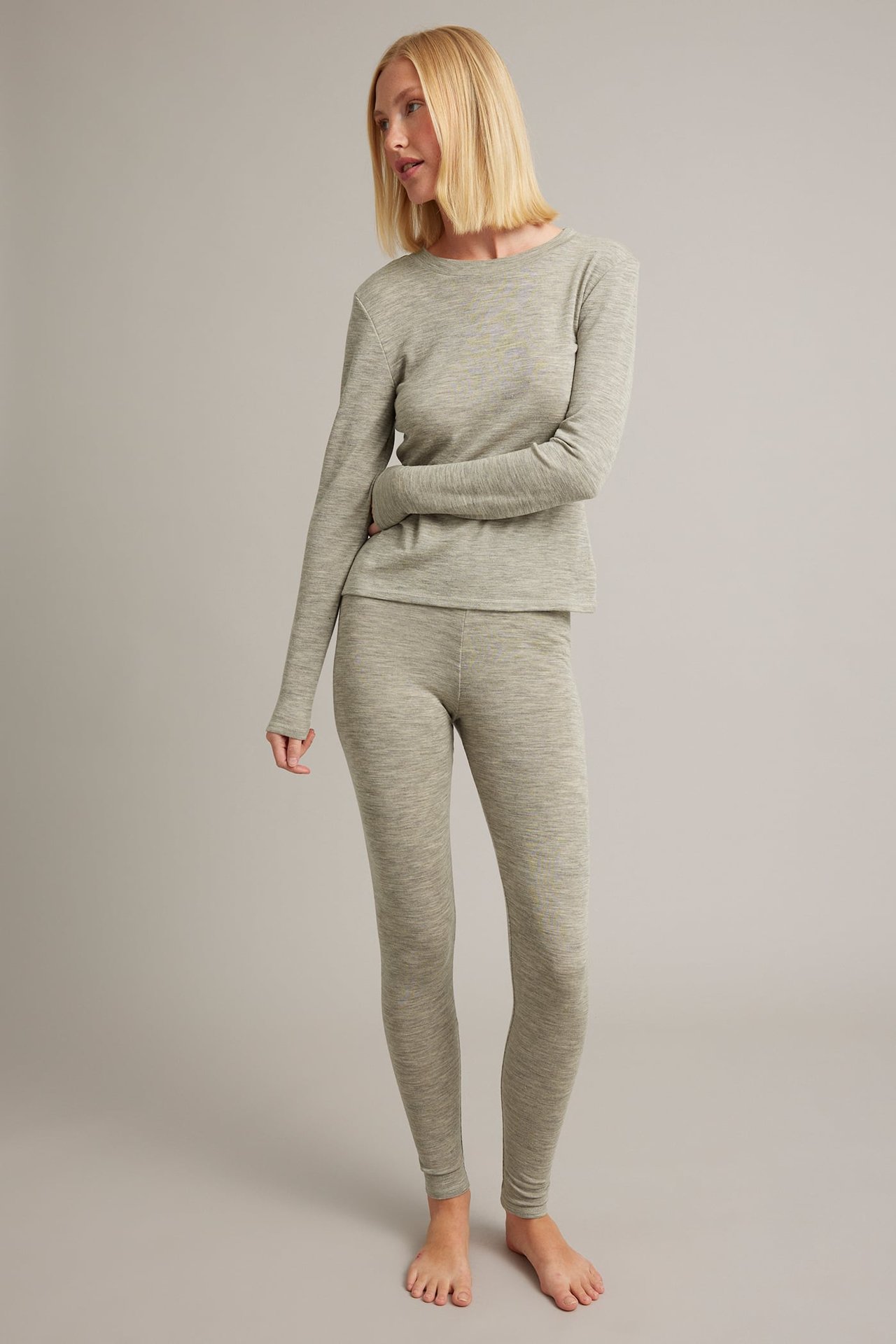 Frontbilde av kvinnelig modell i lys grønn melert langermet topp og matchende leggings.