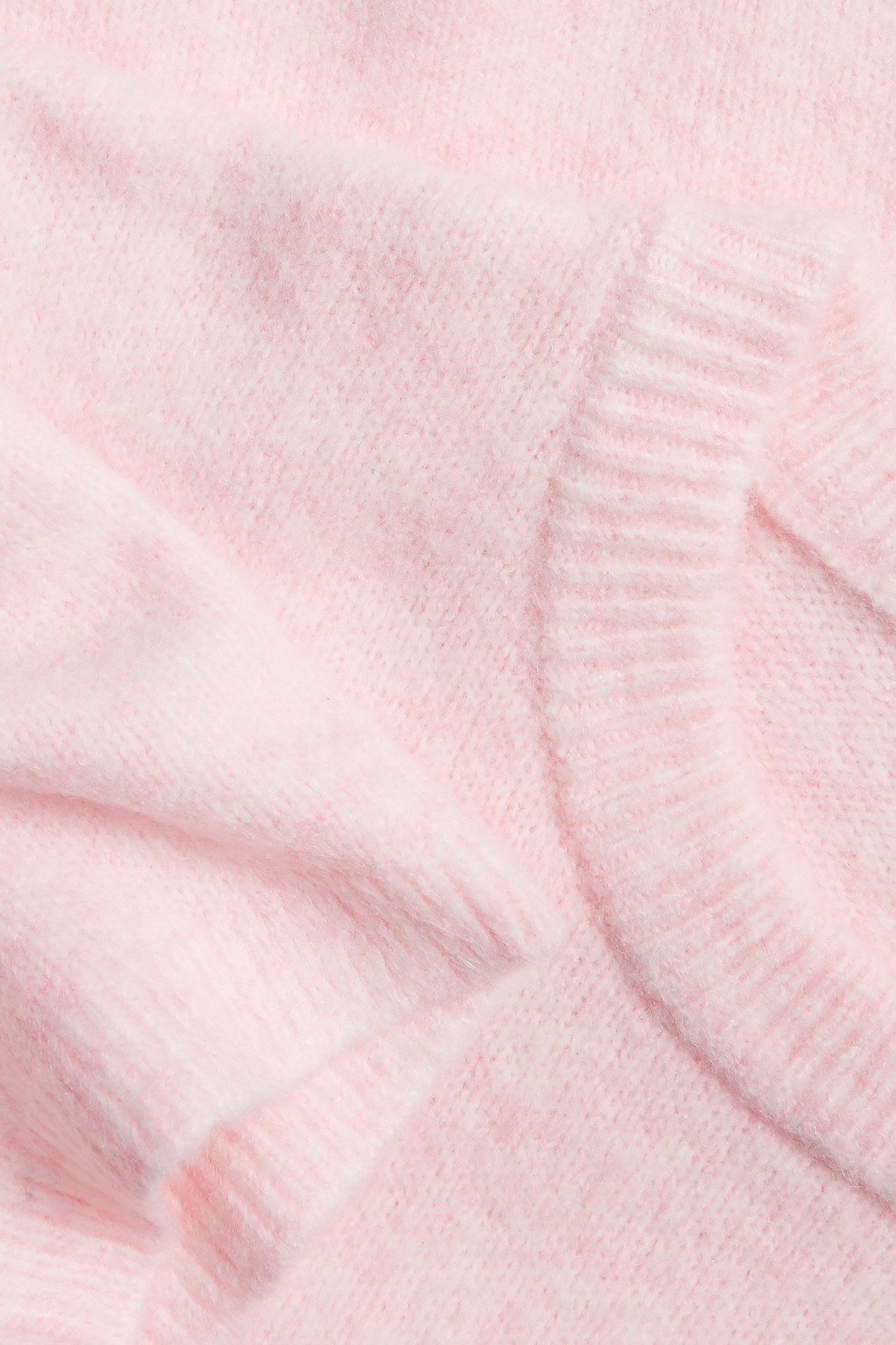 Zbliżenie miękkiego, różowego melanżowego swetra z dzianiny z prążkowanym dekoltem i krótkim rękawem.