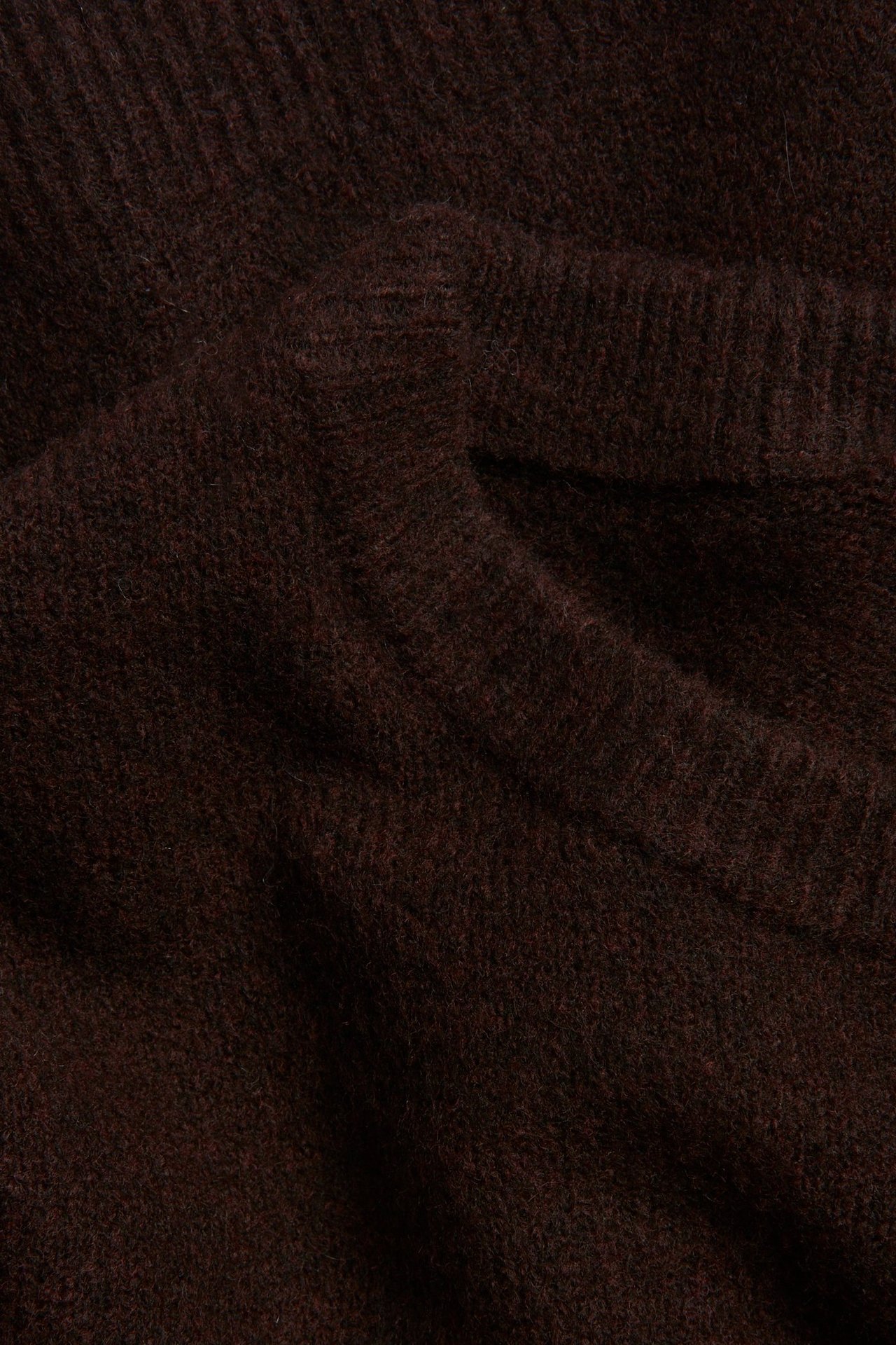 Zbliżenie miękkiego, drobno dzianego brązowego jednolitego materiału swetra.