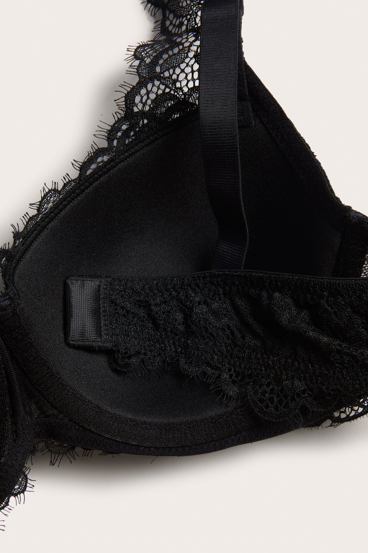 Zbliżenie czarnego, wyściełanego biustonosza koronkowego z koronką rzęsową i regulowanym ramiączkiem.