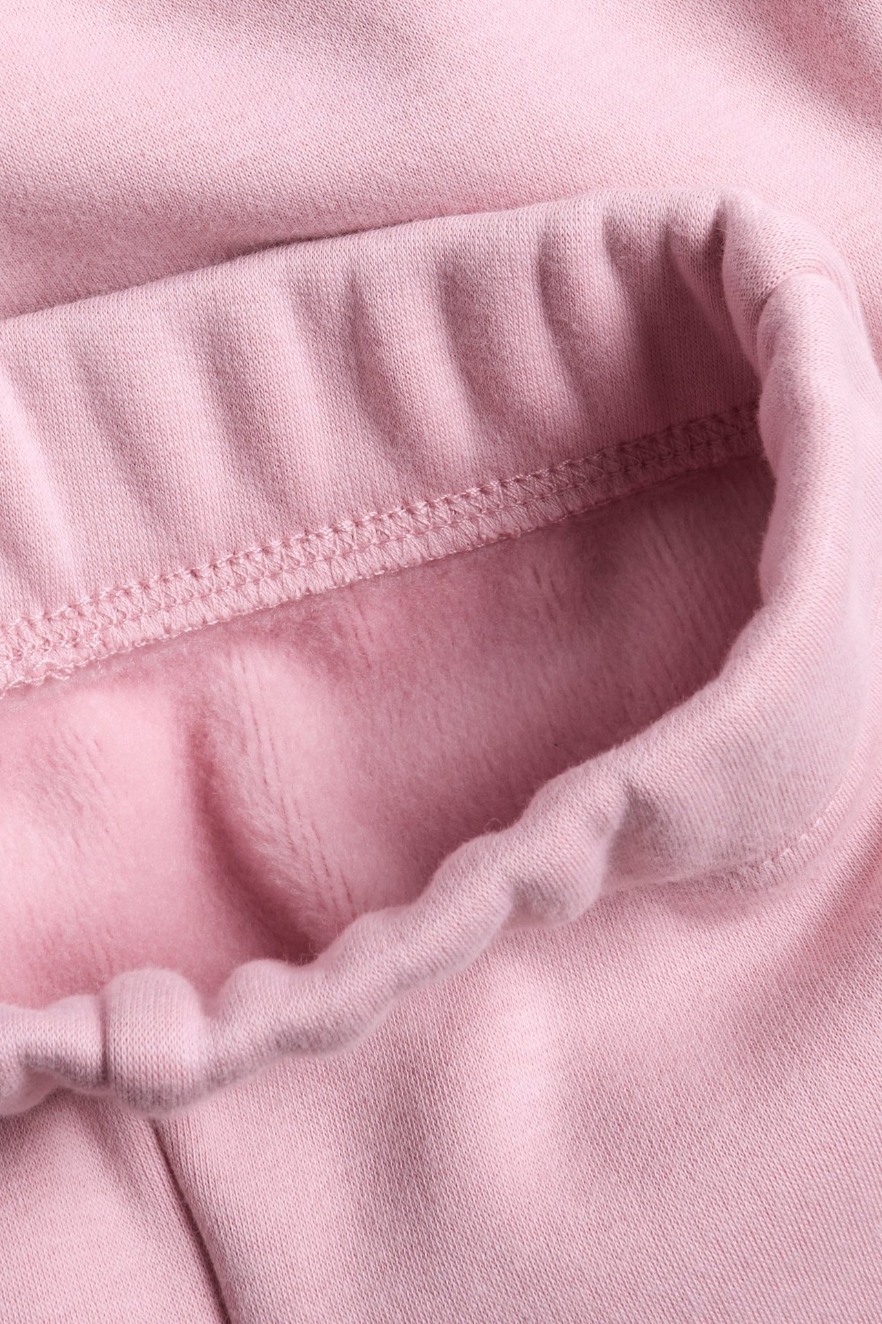 Zbliżenie na jasnoróżowe ciepłe legginsy flare, ukazujące miękkie, szczotkowane wnętrze.