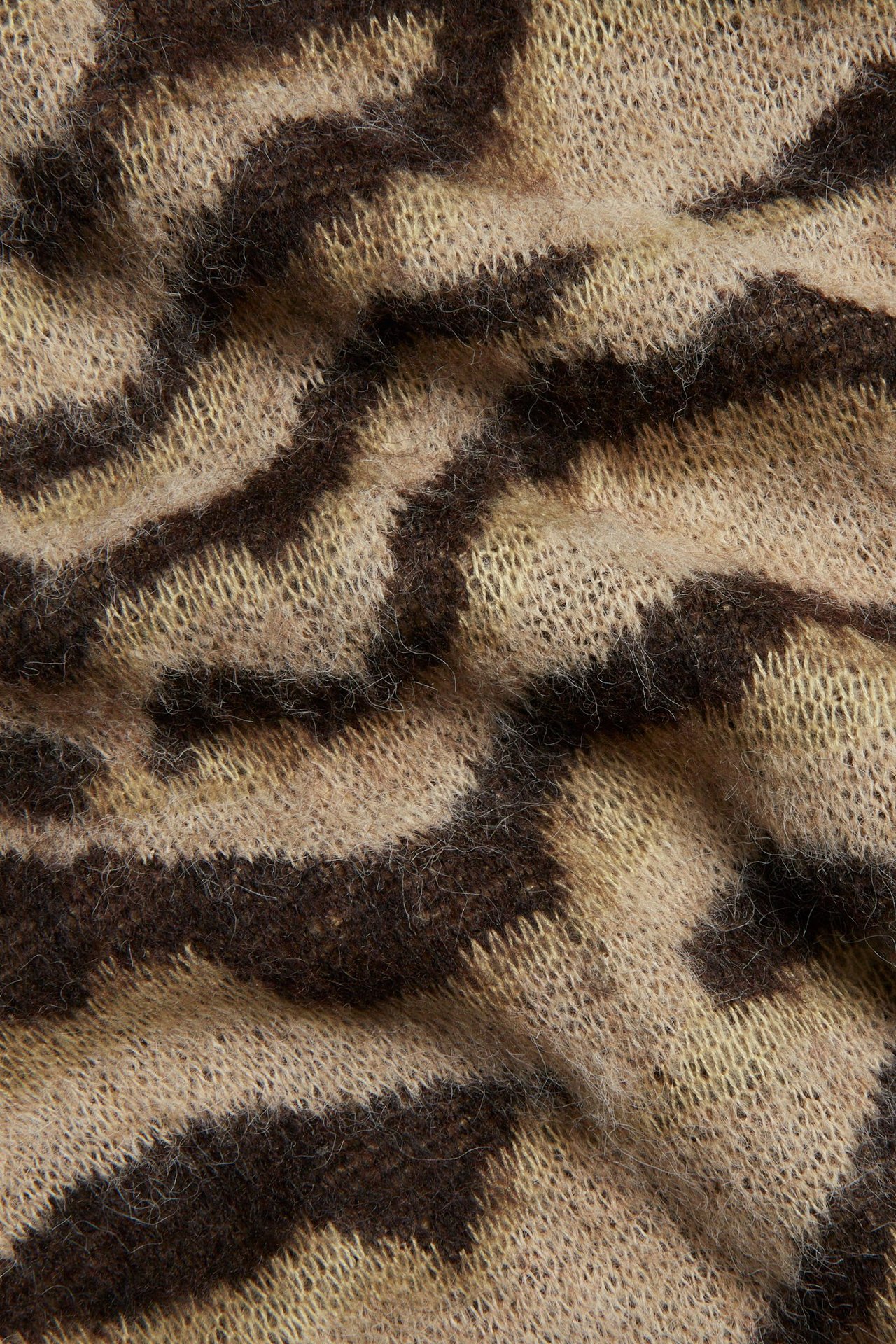 Zbliżenie na puszysty, jasnobeżowy i ciemnobrązowy sweter dzianinowy w zebrę.