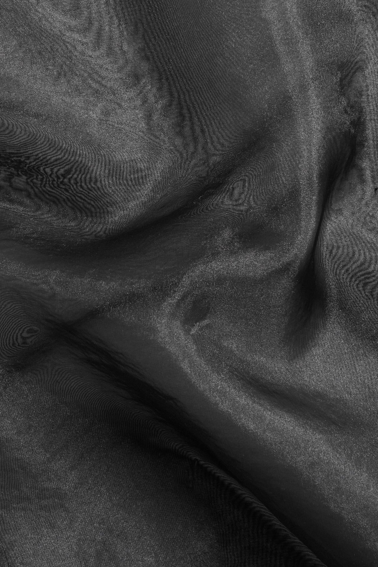 Zbliżenie na czarny, przezroczysty materiał z organzy z widocznymi fałdami i subtelnym połyskiem.