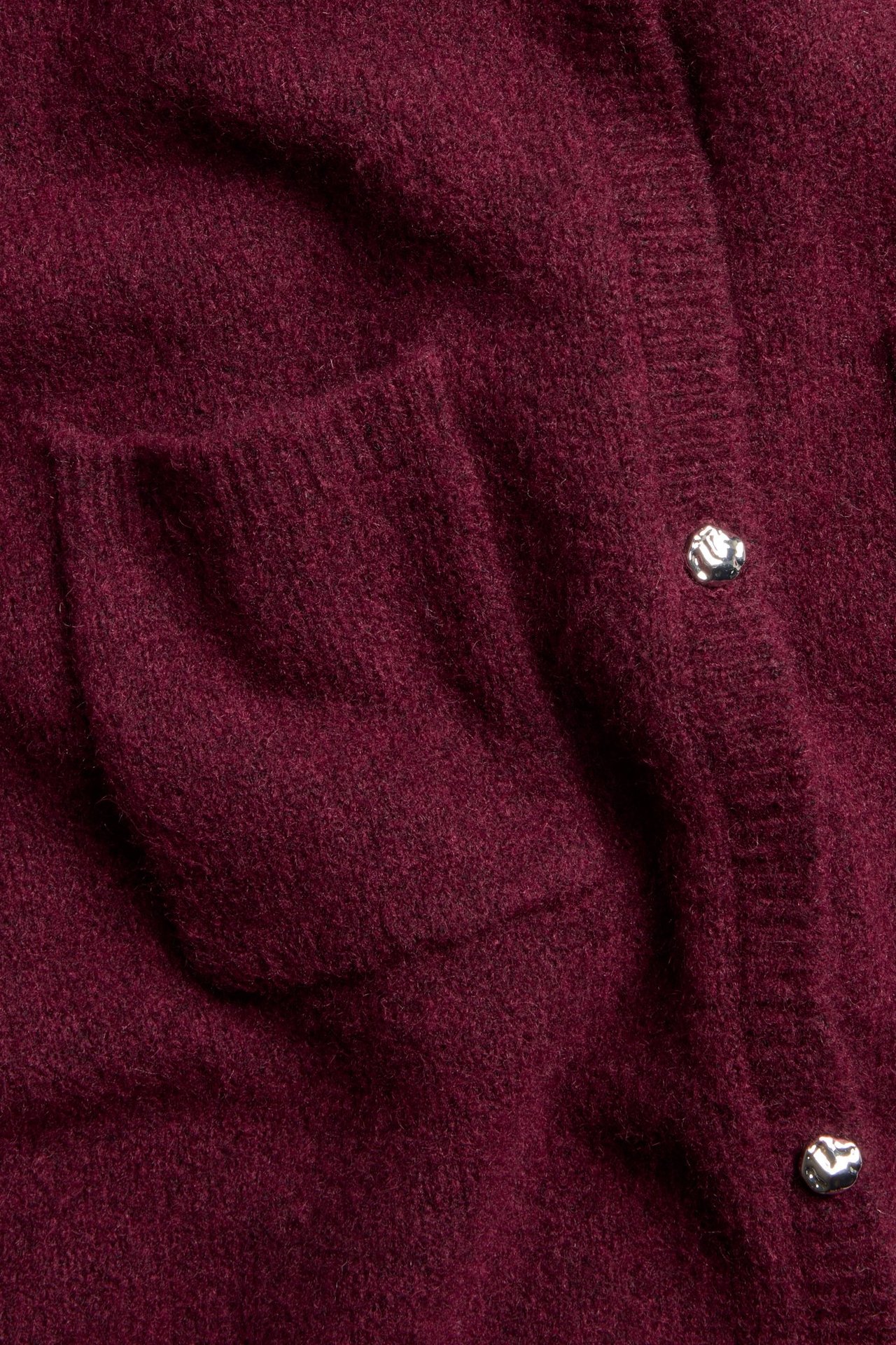 Zbliżenie na bordowy melanżowy kardigan z krótkim rękawem, z kieszenią i okrągłymi metalowymi guzikami.