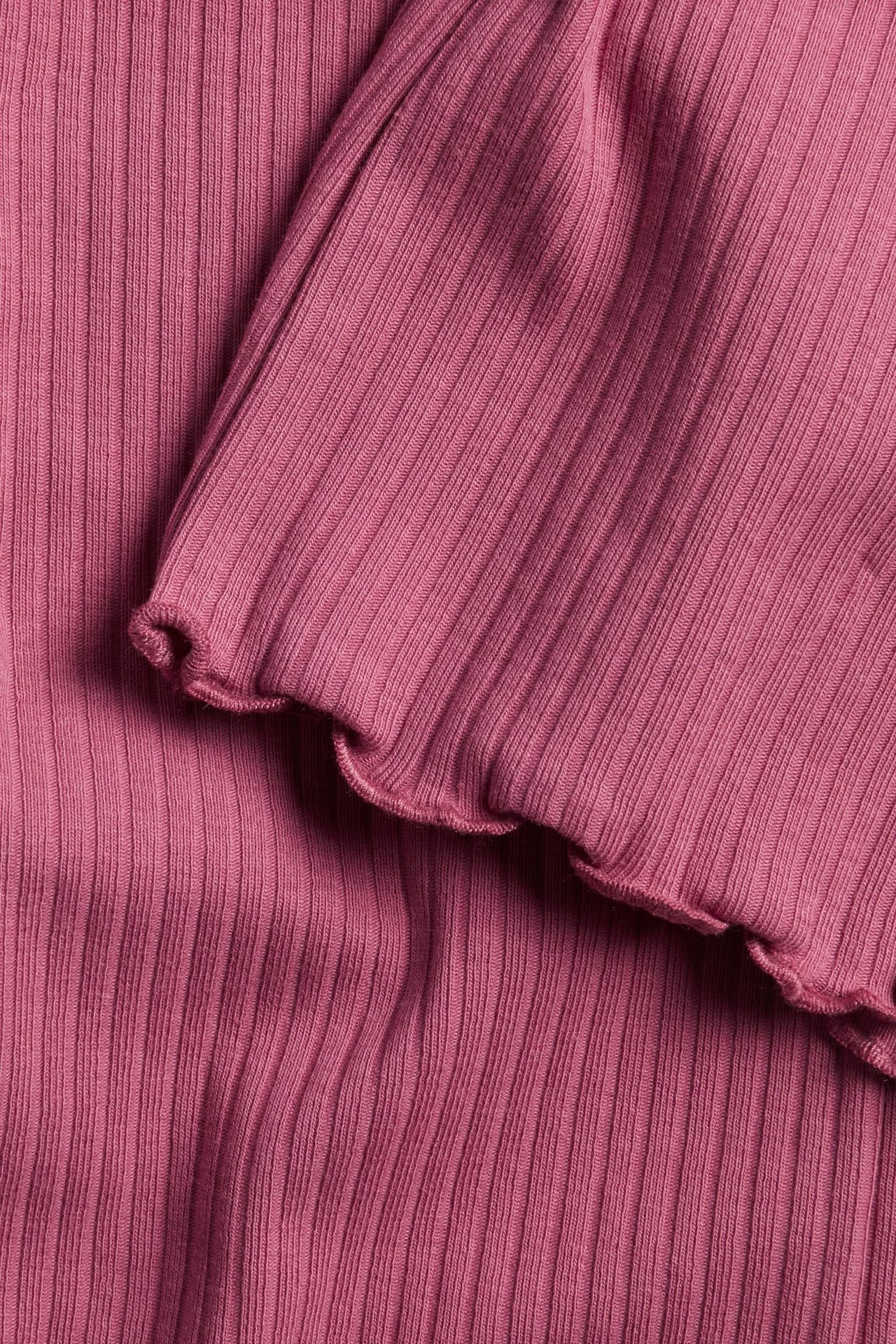 Zbliżenie na ciemnoróżowe prążkowane legginsy flare z wykończeniem babylock.