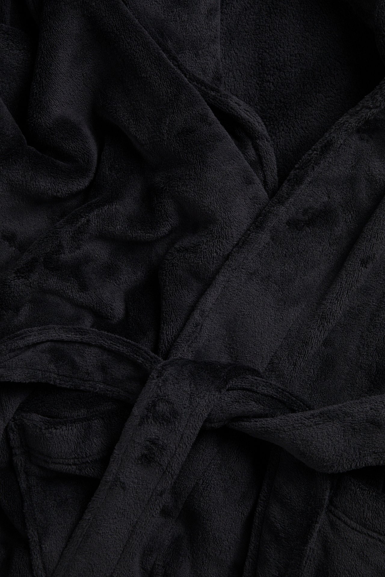 Nærbilde av en svart fleece morgenkåpe med knyttet belte og frontlomme.
